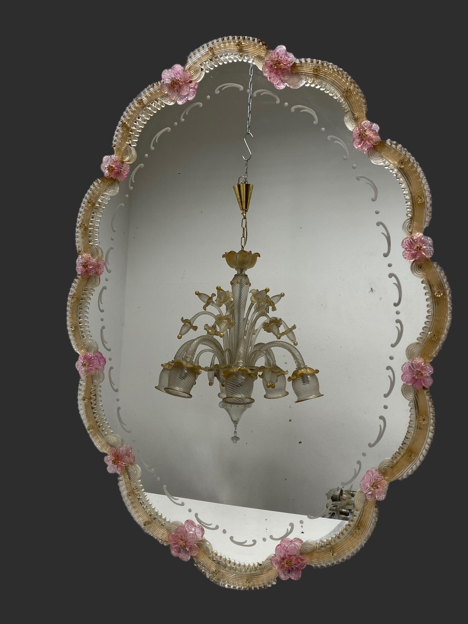 A stunning large Murano glass mirror surrounded with handmade pink glass flowers. It is approx. from the 1960s or older. A view distressed or blind spots in the mirror but this is old-age. With signs of wear as expected with age and use. Obviously