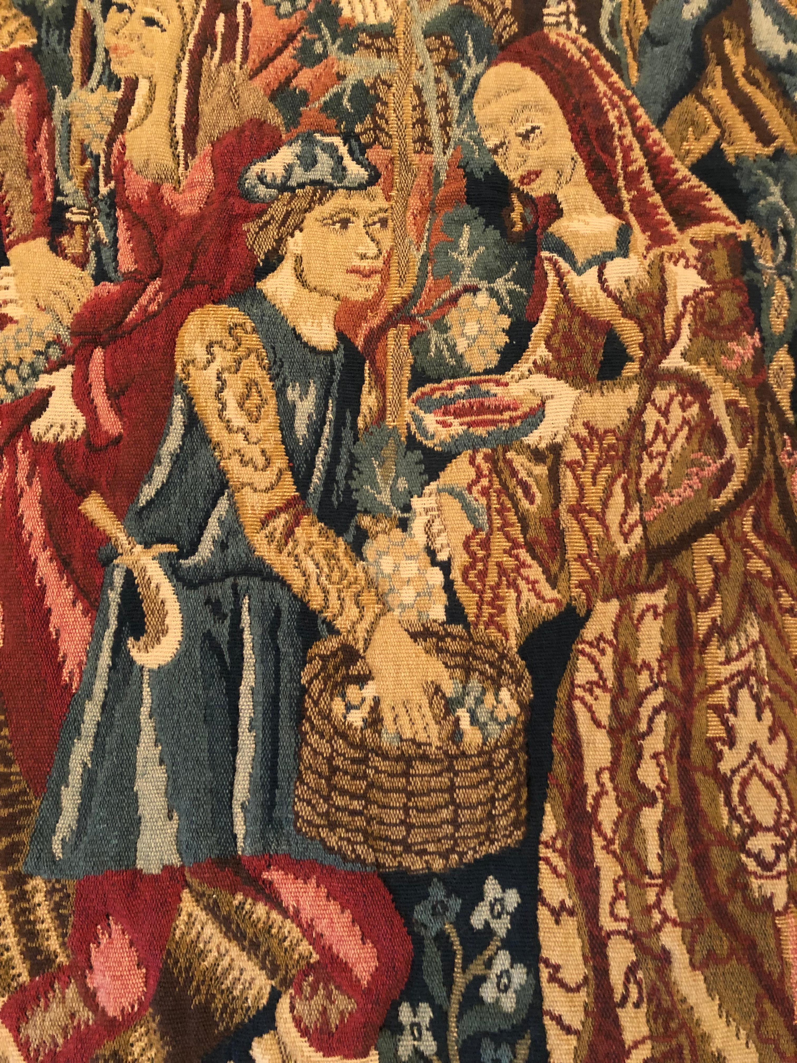 Beautiful richly colored and detailed woven tapestry which is a reproduction of a 14th century French tapestry of period dressed figures picking grapes at harvest.   Made in Belgium.  There's a place on the back to insert a wooden rod for hanging.
