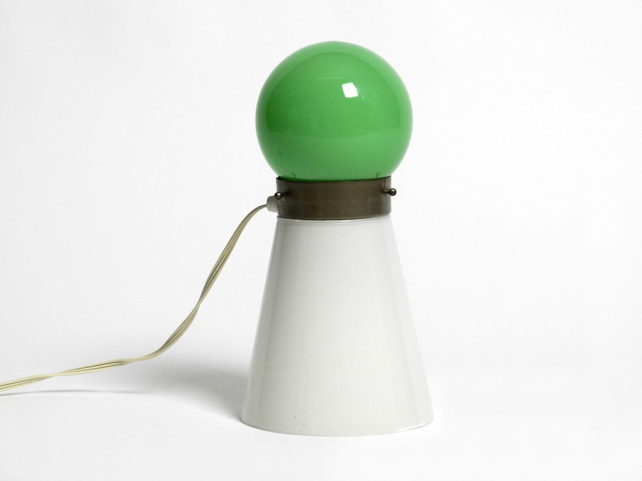 Magnifique lampe de table italienne originale des années 1960 en verre de Murano vert et blanc. 
La forme est celle d'un cône ou rappelle celle d'une pièce de jeu.
Design/One du milieu du siècle en très bon état.
Deux douilles E14 d'origine. État