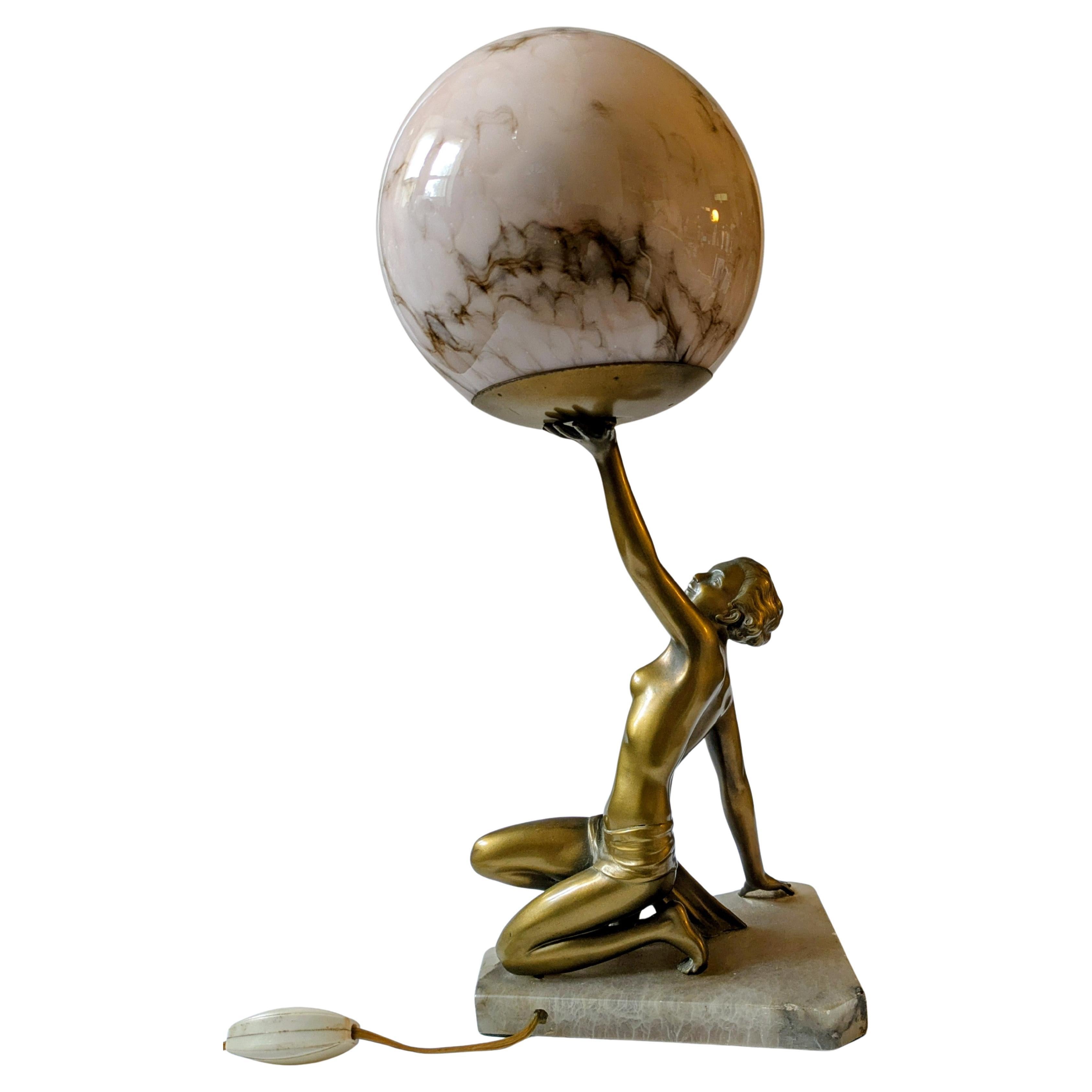 Esta llamativa y auténtica lámpara Art Decó de los años 30 presenta una grácil figura femenina desnuda, bellamente dorada sobre esqueleto y colocada sobre una sólida base de ónice. La escultura capta la elegancia y el movimiento característicos de