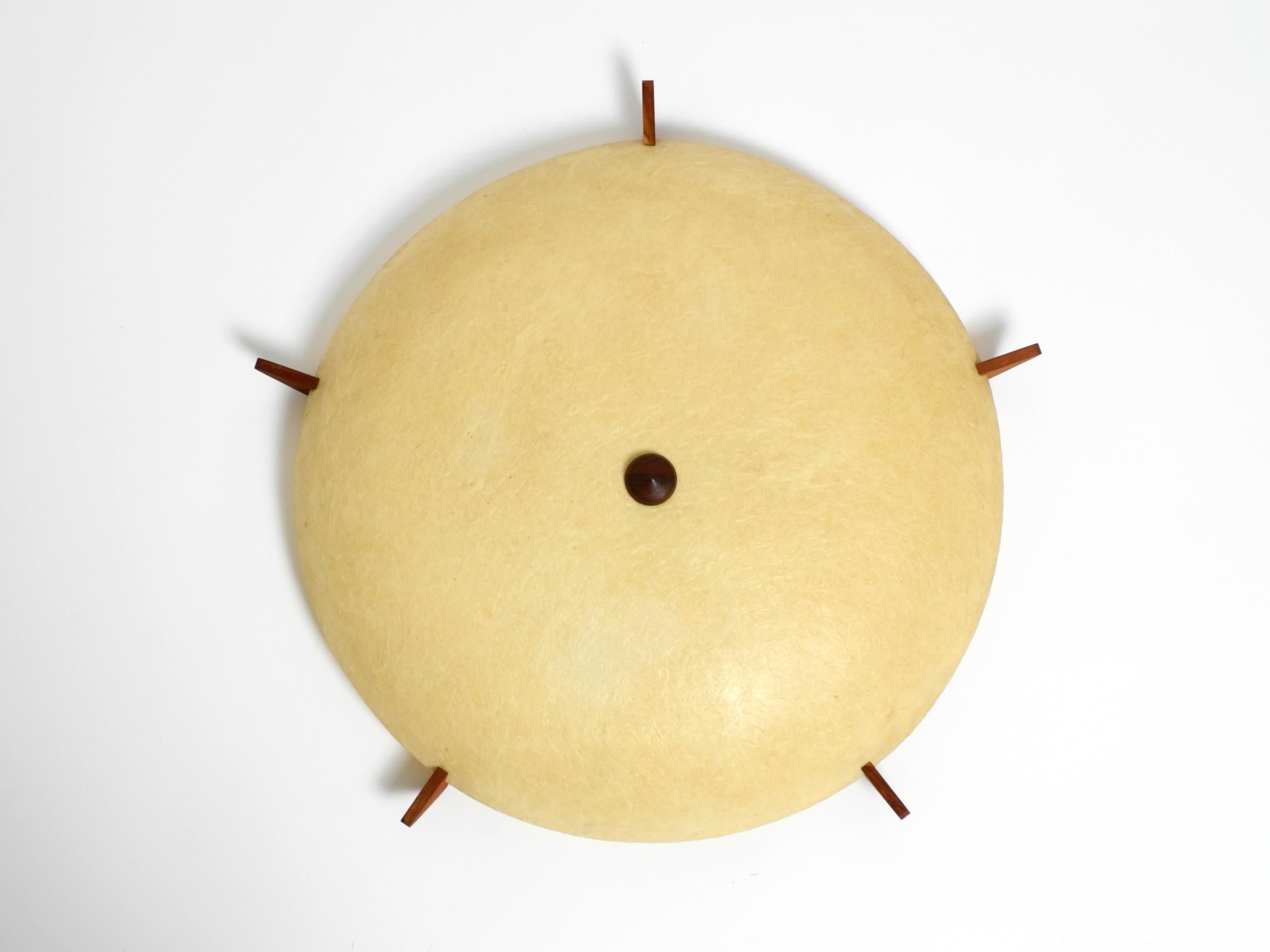 Bellissima lampada da soffitto o da parete in fibra di vetro beige, in stile Mid Century Modern. 
Cinque elementi in teak sono inseriti lungo i bordi. Queste tengono la lampada saldamente in posizione sul soffitto o sulla parete. 
Anche la vite al