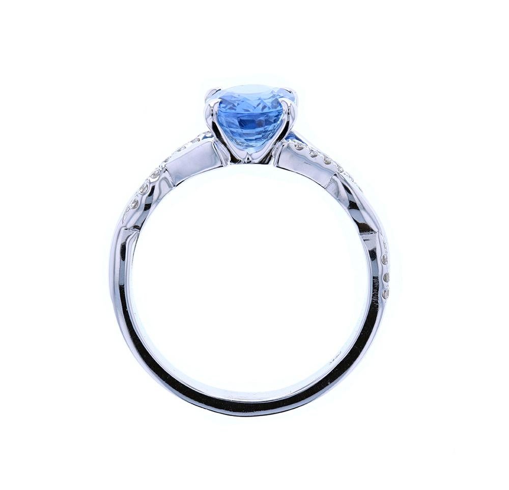 This stone reminds us of the ocean!  A beautiful oval sapphire center stone is set in a custom engagement ring with diamond pave. A twisted shank provides movement to the design of the pieces, which interweaves a bare shank around the one with the