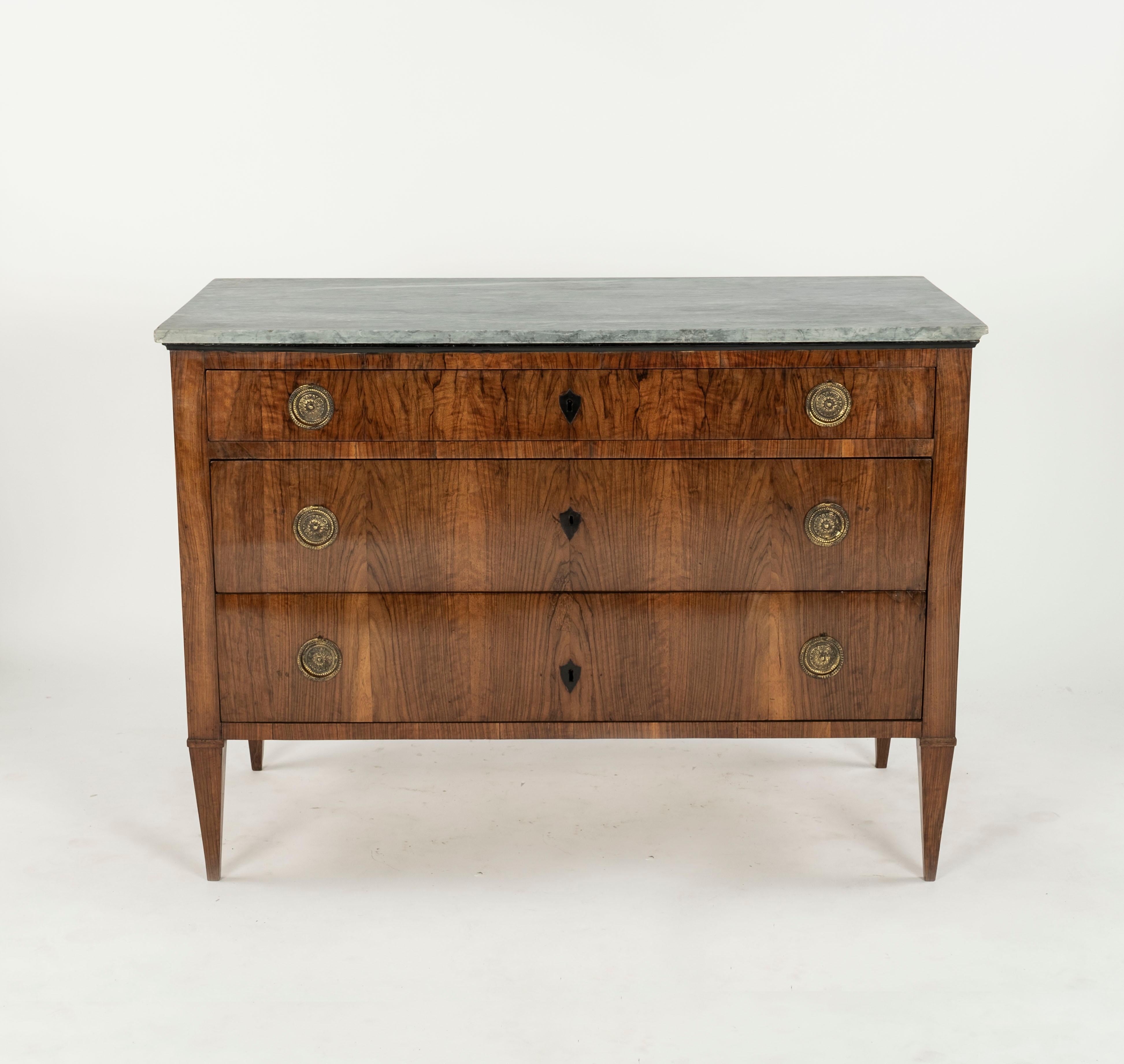 An exceptionally stylish pair of early 19th Century three drawer chest of drawers with good use of matching walnut to fronts. Having original marbles on top. The drawers having ebonised escutcheons and brass drop pull handles. Standing on square