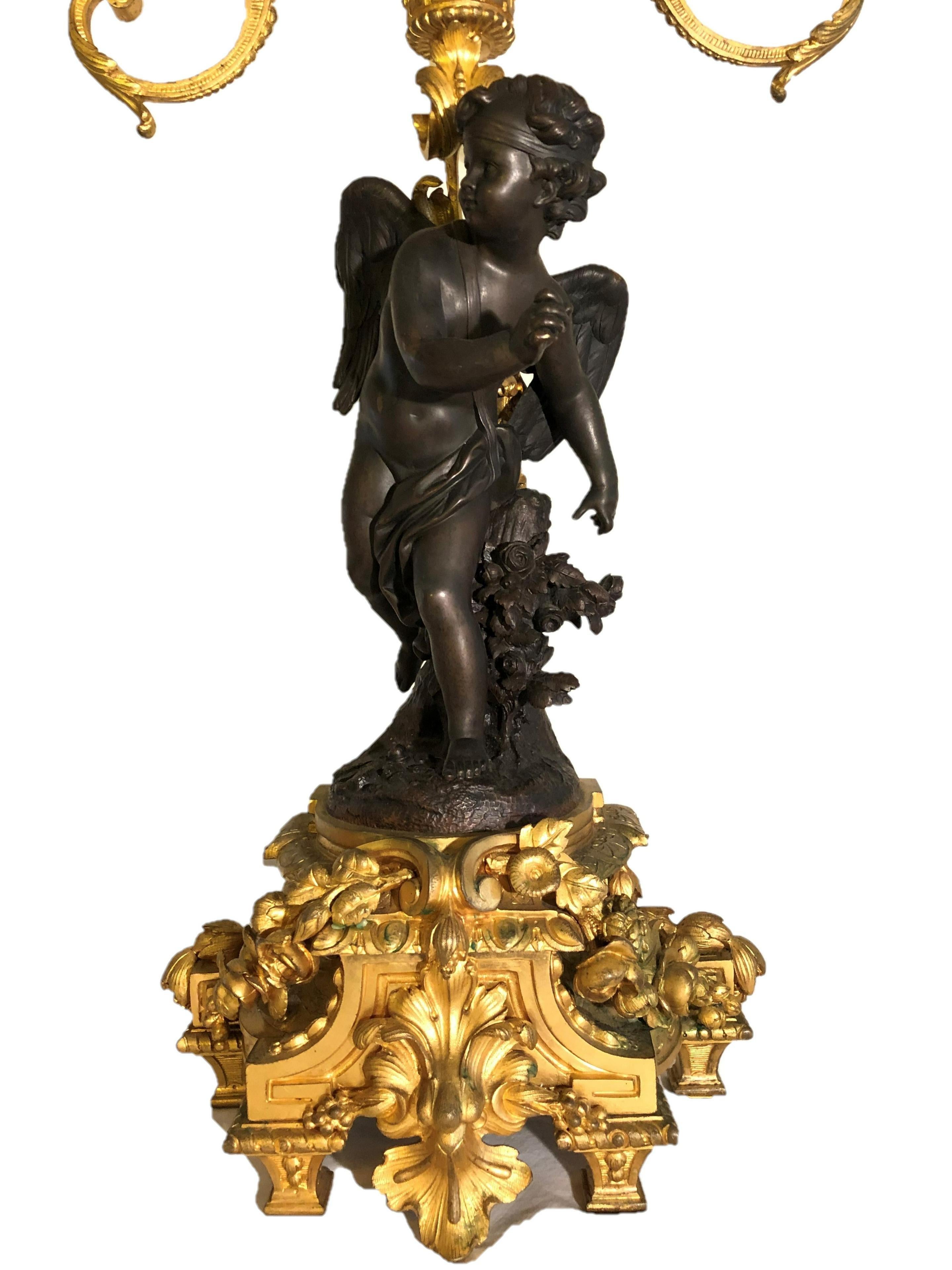 Beautiful pair of 19th century French Louis Philippe patinated bronze and gilt bronze candelabra. Cupid and a female. Fine quality bronze doré leaf and flower bases. Two tiered candelabras.