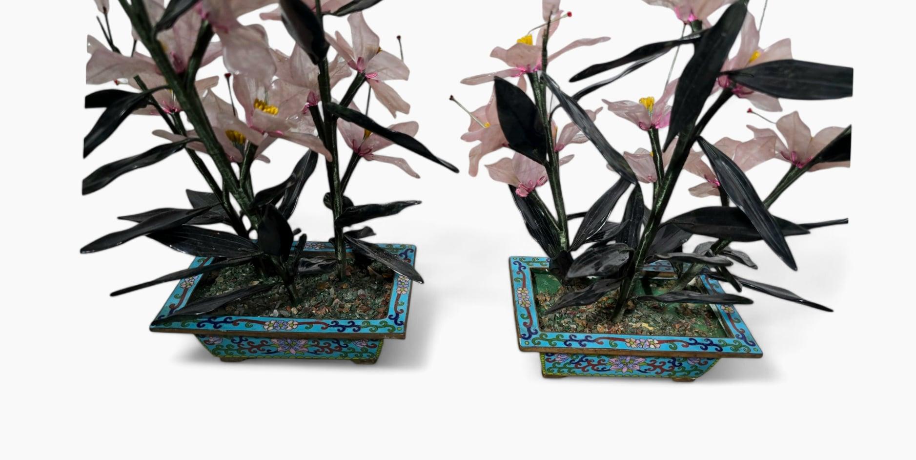This exquisite pair of bonsai trees from the 20th century features vibrant, hand-crafted leaves and flowers made from agate, crystal, and nephrite jade. The trees are set in intricately designed cloisonné enamel copper flower pots, adding a touch of