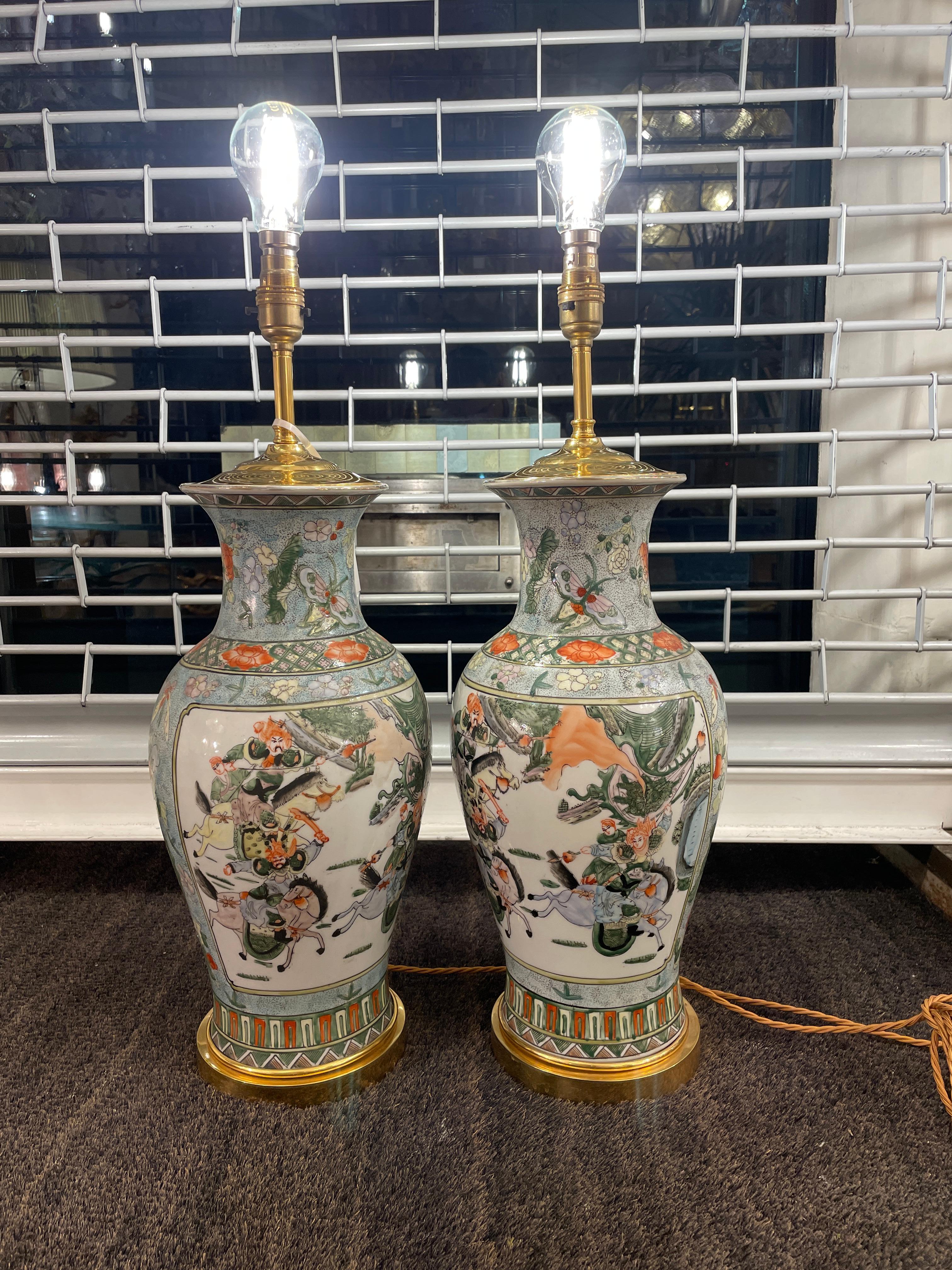 Beautiful pair of ceramic vases decorated in the Chinese style sitting on a gilt brass circular base. 
Decorated with Chinese style figures on horseback, butterflies and flowers.

Height described as to top of bulb fitment unit
Base 15.5cm