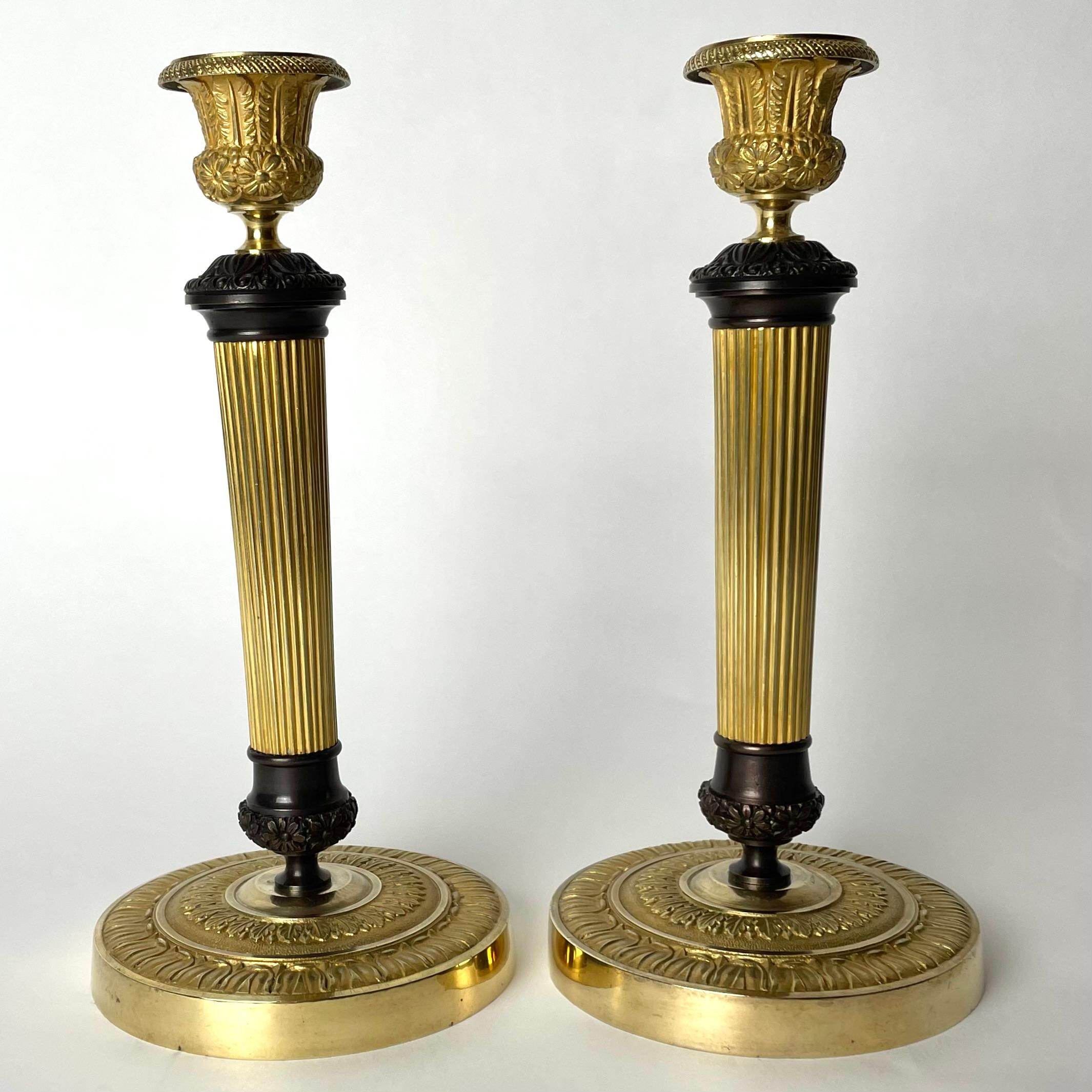Wunderschönes Paar Empire-Kerzenleuchter aus vergoldeter und dunkel patinierter Bronze. Hergestellt in Frankreich in den 1820er Jahren. Sehr zeitgemäßes Design mit Blumen und Blättern. Kühle und ungewöhnliche Komposition zwischen vergoldeter und