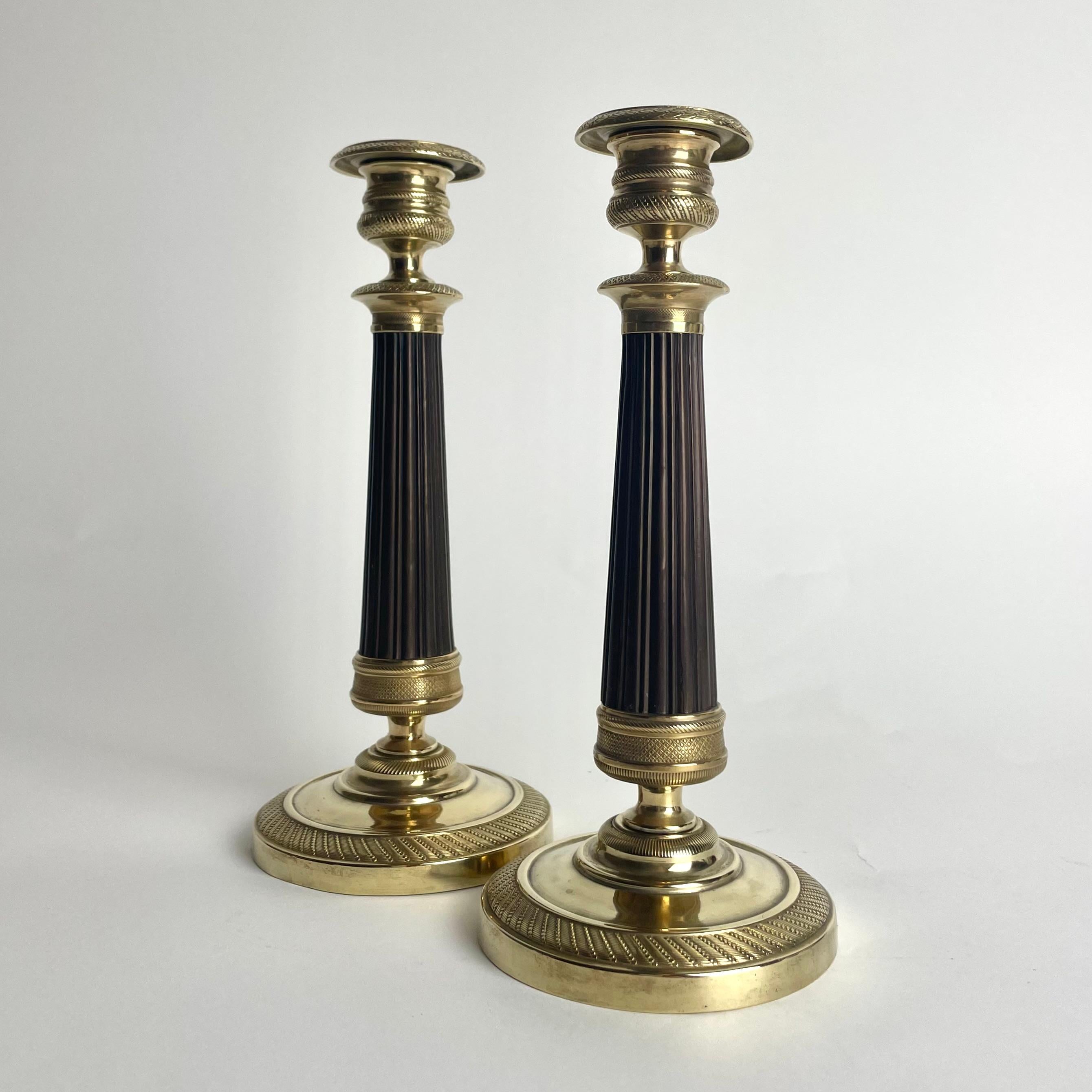 Pequeña y hermosa pareja de candelabros Imperio en bronce dorado y patinado oscuro. Fabricado en Francia durante la década de 1820. Diseño muy de época.

Desgaste propio de la edad y el uso 
