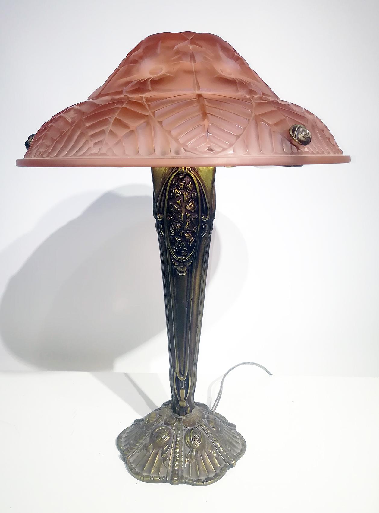 Charming pair of Art Deco table lamps, high quality molded glass panel (diameter: 35 cm ), hat shaped in grenadine color with original floral and leaves motif design signed “Ranc Freres”, resting on a bronze column with detailed floral