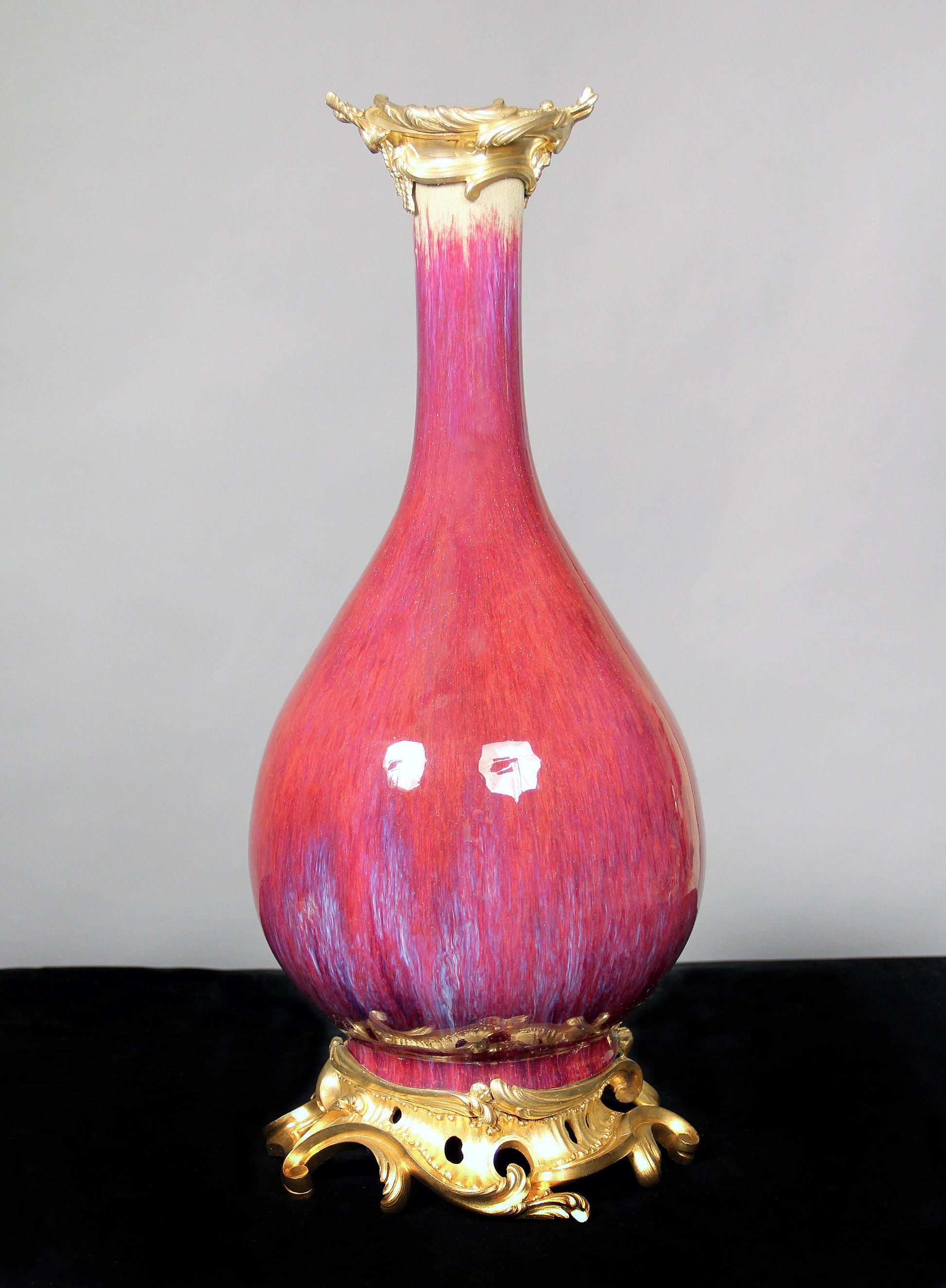 Lovely “Sang de Boeuf” French porcelain with gilt bronze tops and sitting on a designed gilt bronze stand.

Sang de Boeuf, also called flambé glaze, a glossy, rich, bloodred glaze often slashed with streaks of purple or turquoise used to decorate