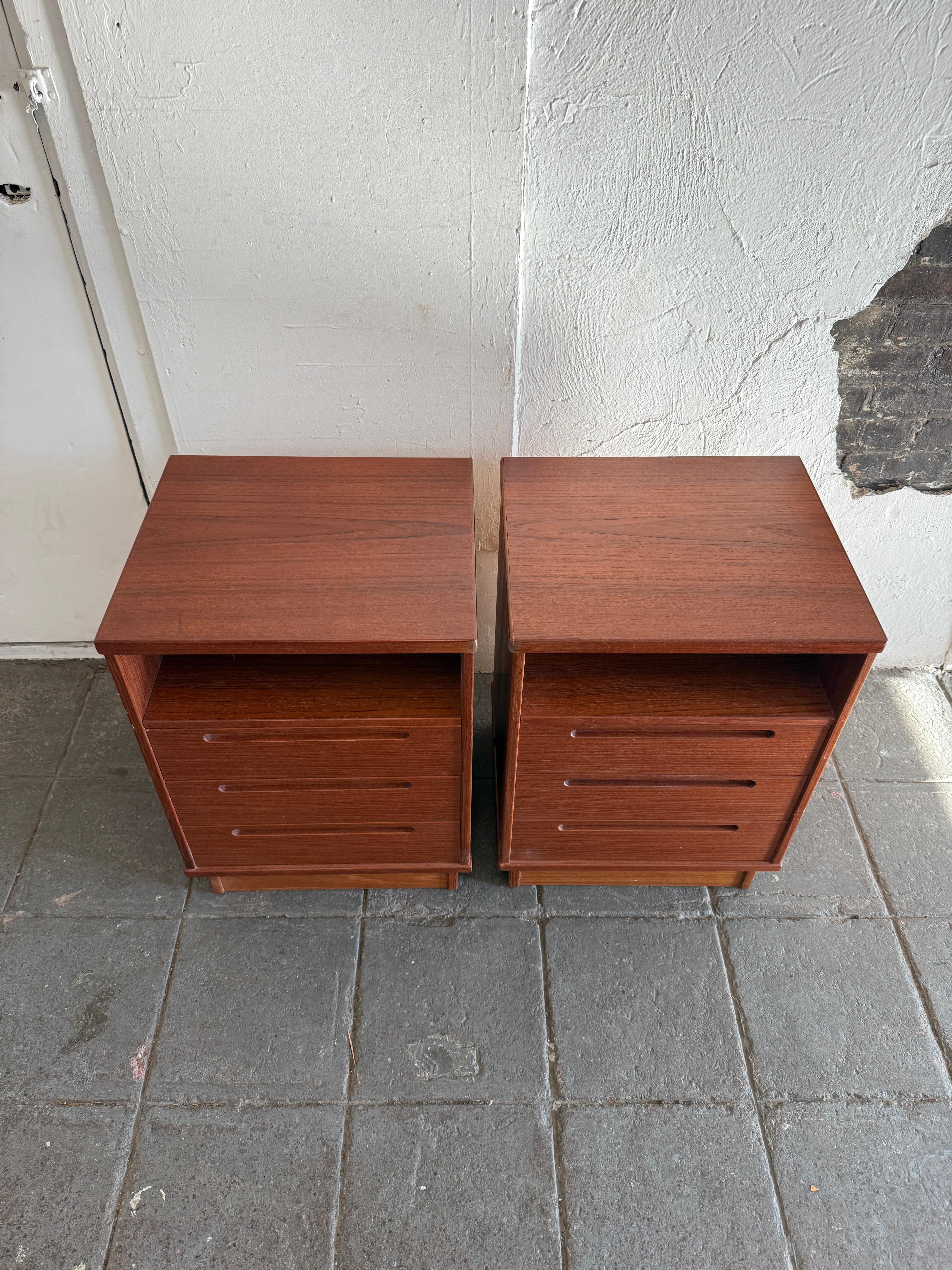 Precioso par de mesillas de noche de 3 cajones de teca moderna de mediados de siglo, fabricadas en Dinamarca. Diseñado por Nils Jonsson para HJN Mobler. Cuerpo cuadrado y base de plinto. Un cubículo y 3 cajones inferiores con tirador embutido. La