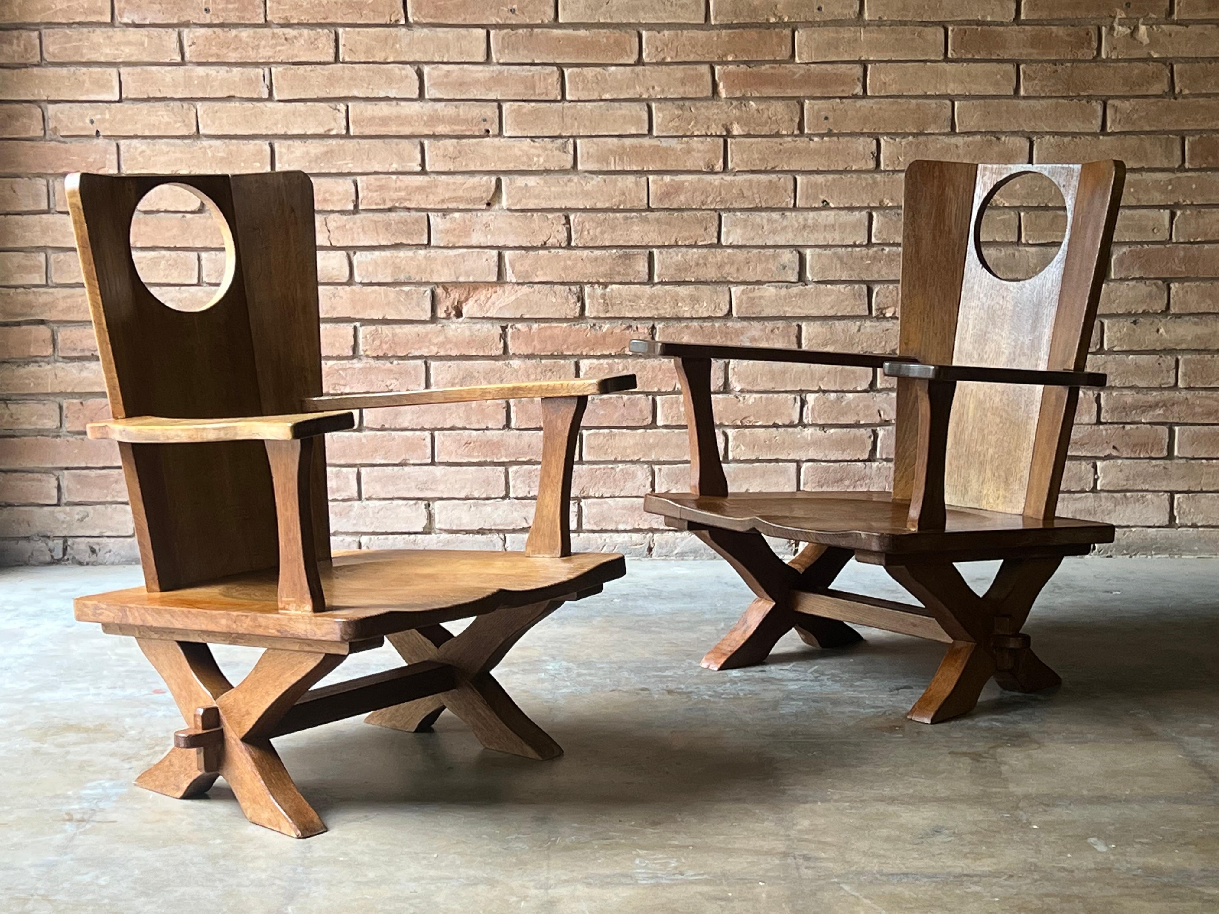 Pair of uncommon low arm chairs in oak likely manufactured in Belgium or the Netherlands, c. 1970s. They are sculptural and well made, while being functional and comfortable. A lovely constructive quality to them. These certainly check all the