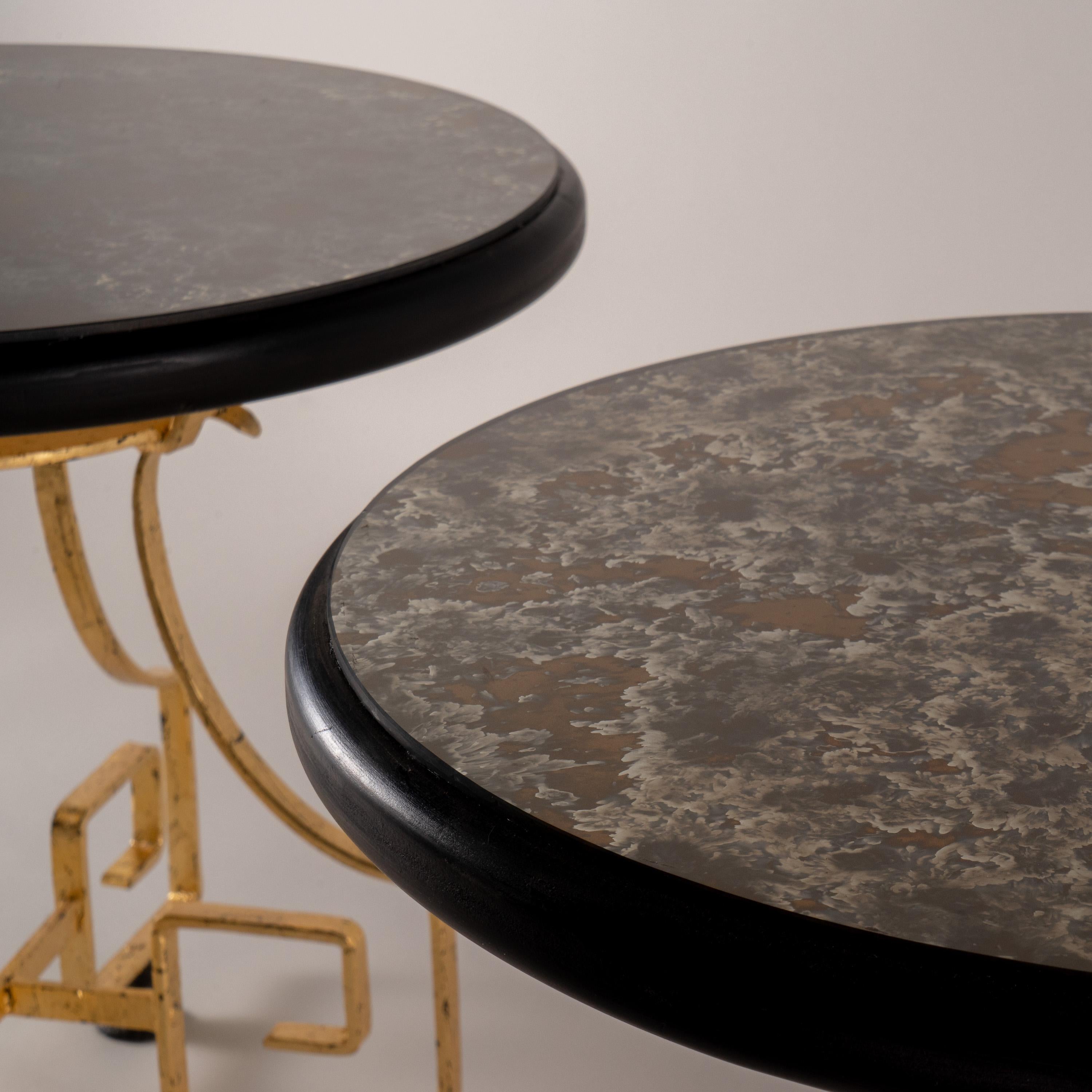 Two sturdy side tables attributed to Arturo Pani (Mexico 1915-1981) of wrought iron lacquered in black and gilded with foil. At the top, a thick wooden base lacquered in mate black and attached to it a rounded acid-stained mirrored glass. The iron