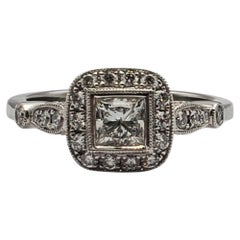Precioso anillo de compromiso de platino con halo central de talla princesa