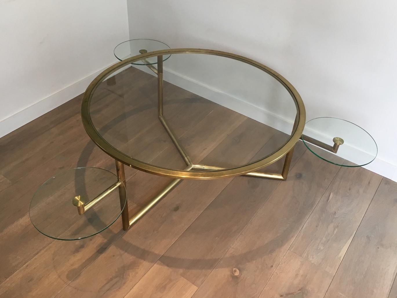This rare round coffee table is gold gilt on chrome. The gilt left a little bit on some areas, which gives it a great patina. It is very nice and convenient with its removable round glass shelves that are a way to extend the table. It is French,