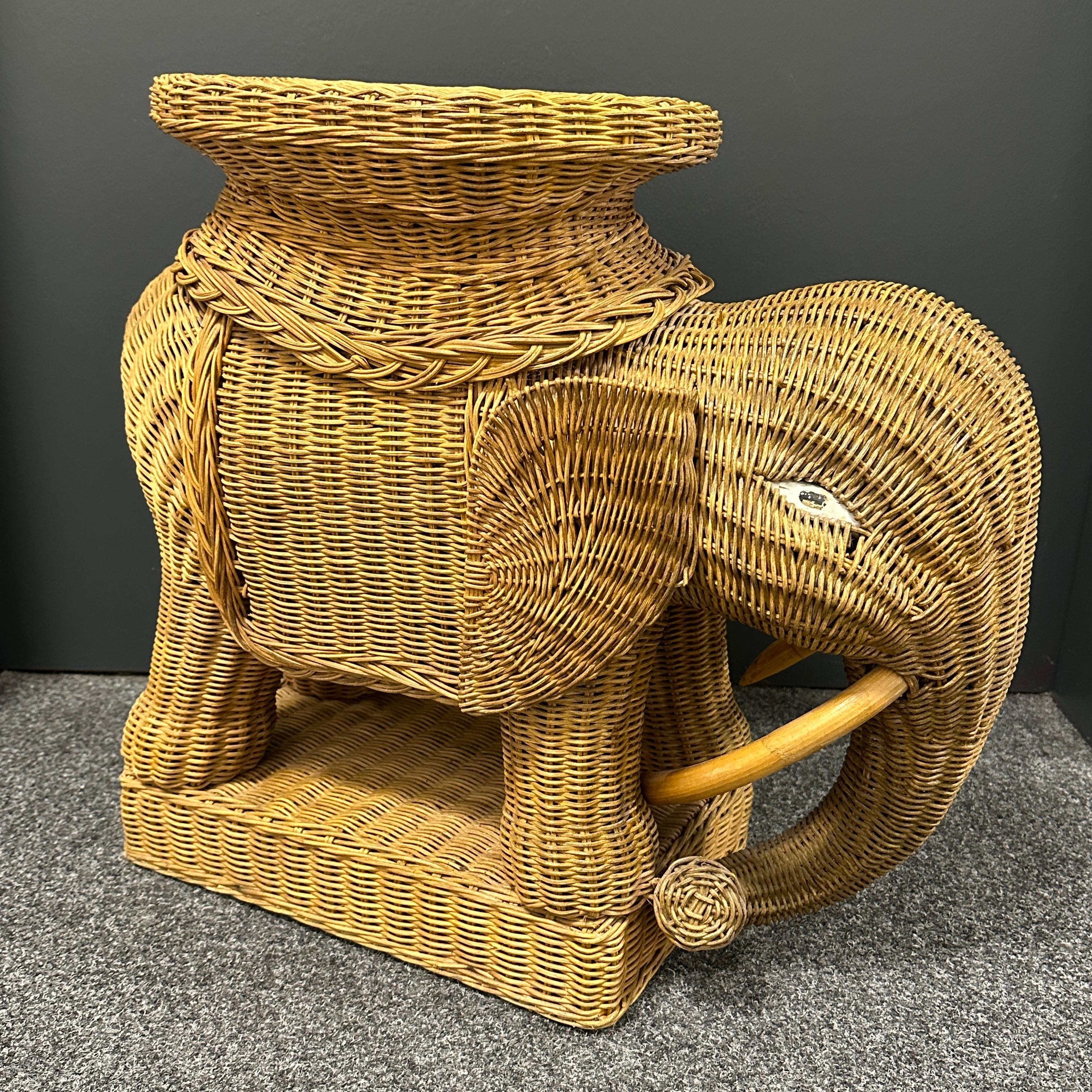 Mid-20th century eye-catching elephant-shaped end table or side table, constructed in hand-braided rattan accented with wood tusks. Nice addition to your home, patio or garden. This is in used condition, with signs of wear as expected with age and