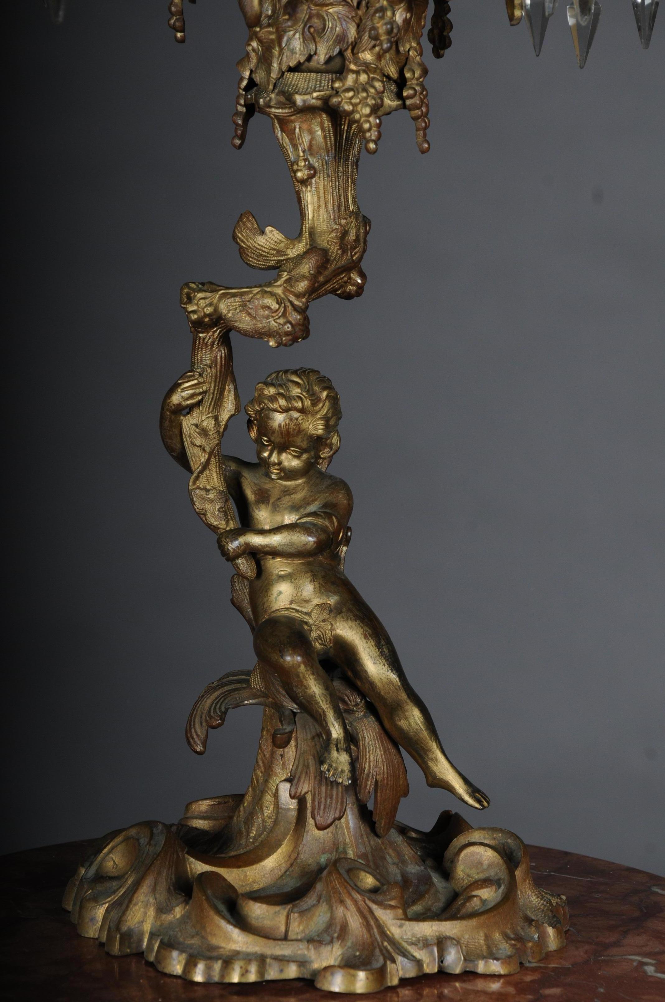 Rococo candlesticks Bronze gilded, circa 1870.

Antique, weighty and richly decorated Rococo bronze candlestick with prismatic blinds. Putto holding a candle crown which consists of 7 lighthouses. Extremely decorative and finely