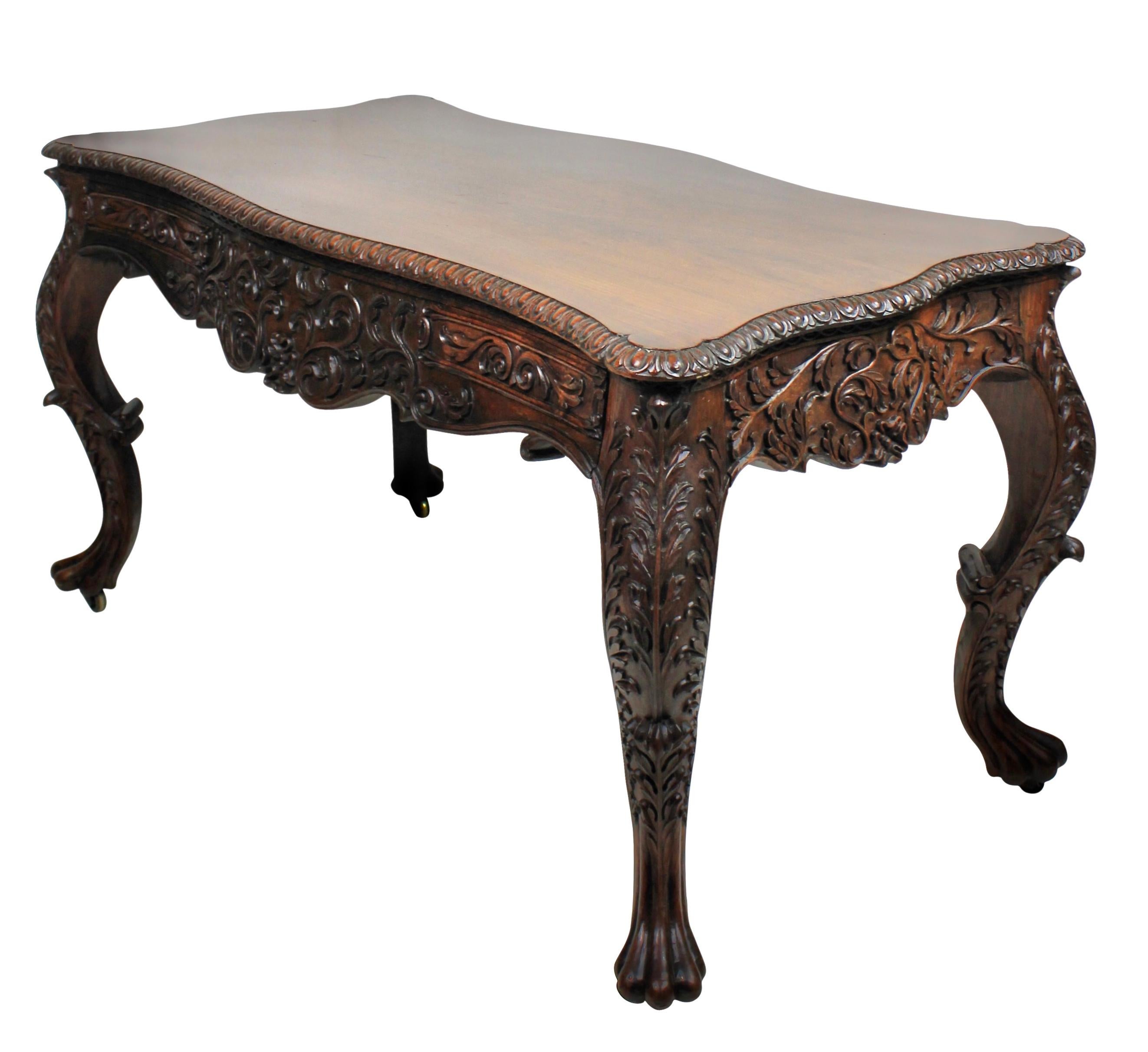 An Anglo-Indian serpentine library table of exceptional quality in solid rosewood. The intricate carving, which goes fully around & includes two drawers on one side & two ''dummy'' drawers on the other, is absolutely superb. The swept cabriole legs