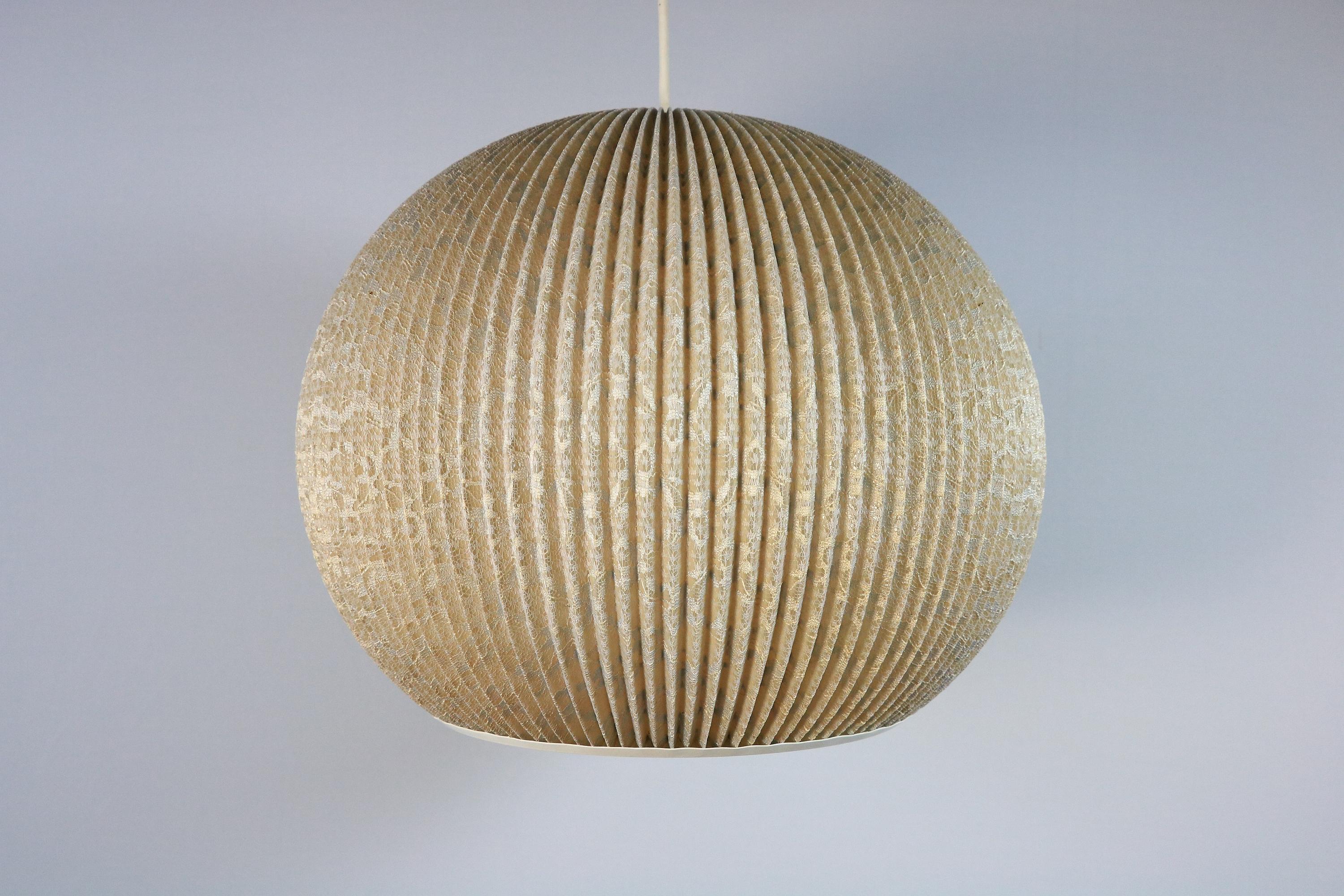 Very decorative pleated hanging lamp from the GDR.
Original 1960s.
 
Interesting lace pattern that is particularly effective when lit.
 
The material is fabric (lace pattern) on a hard plastic ground. The openings at the top and bottom are edged