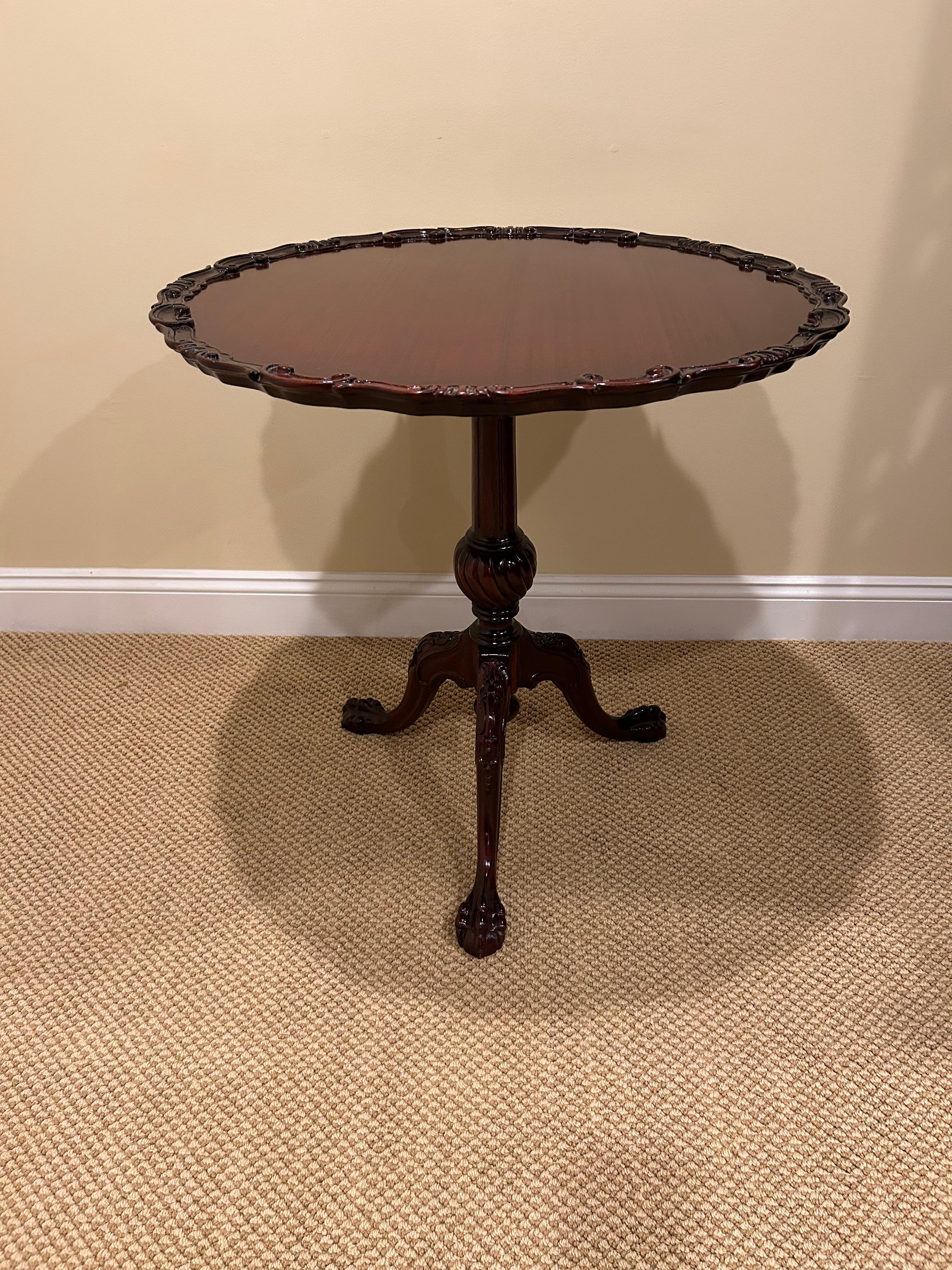 Preciosa mesa basculante lateral redonda hecha a medida, con tablero de caoba de hermosas vetas, base de pedestal tallada con patas de trípode terminadas en garras y borde ornamentado tallado alrededor del tablero. Toda la superficie se inclina