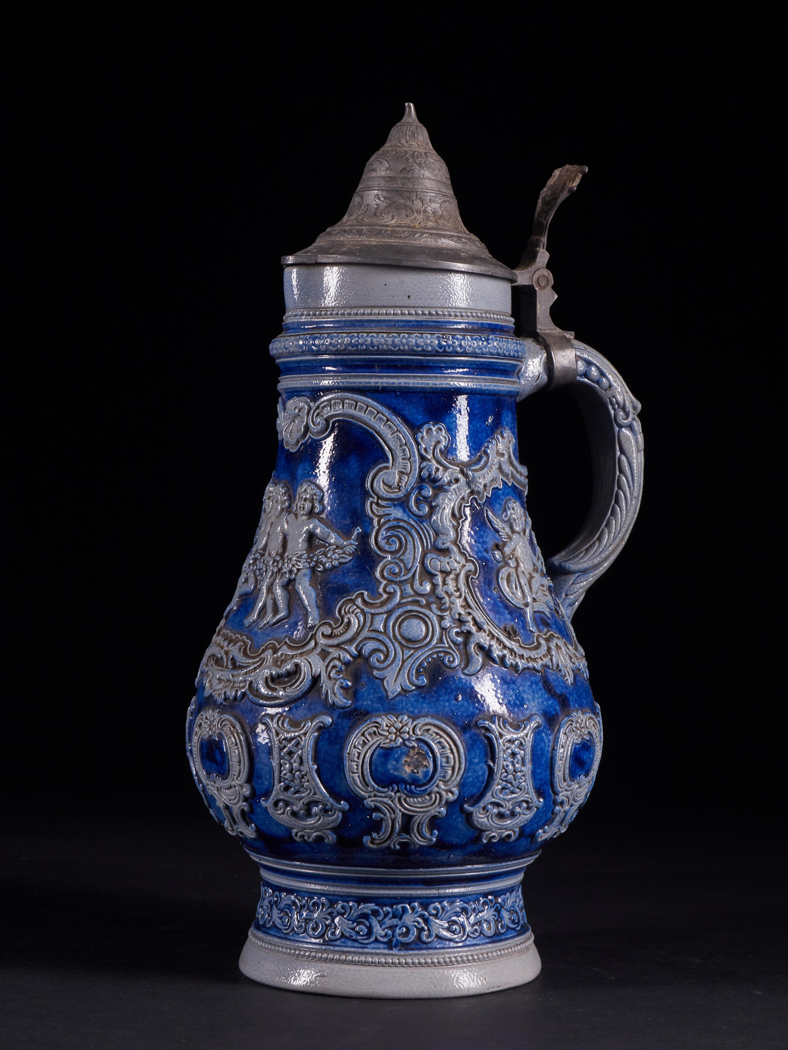 Highly detailed and unique set of 4 vintage faïence beer carafes with relief, indigo blue elements, and thumb-operated metal lids. Very good condition. Tags on the bottom: none / 524 / 899 / 1496 A.