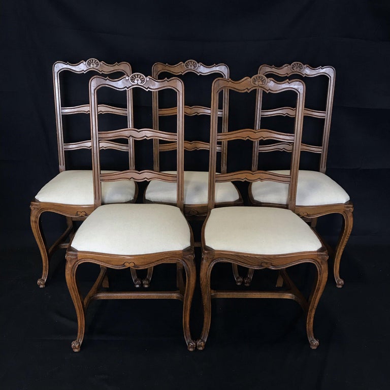 Set of five antique country French walnut dining side chairs, featuring the traditional arched seatback crown, with ladderback design supported by a finely styled framework and apron, ending in classic escargot tips on the feet. Great for dining