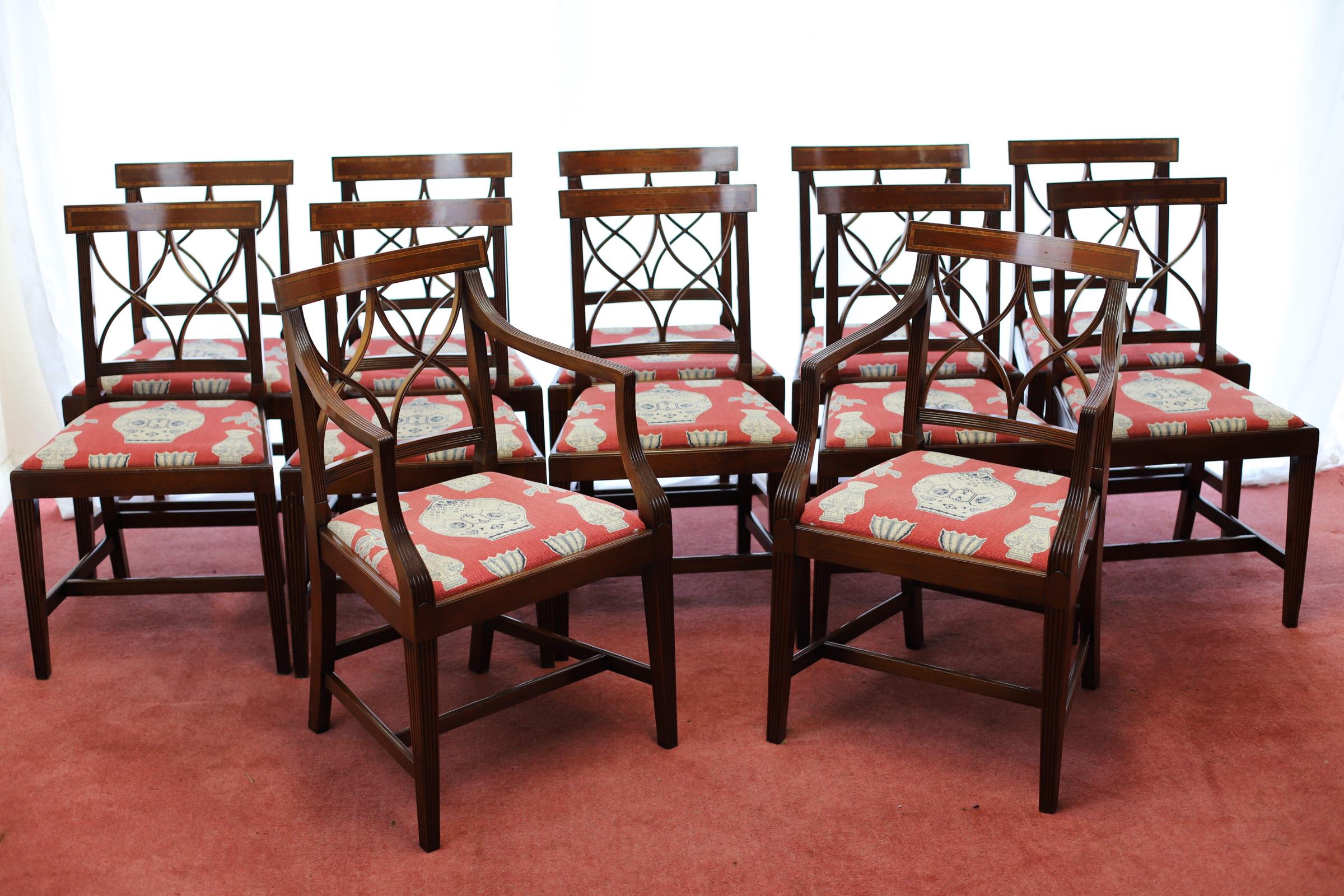 Wir freuen uns, dieses erstaunliche Set von zwölf Mahagoni-Esszimmerstühlen im Stil von George III. zum Verkauf anbieten zu können, darunter ein Paar offener Sessel. Die Stühle sind mit Tulipwood gekreuzt und mit ebonisierten Linien eingelegt, die