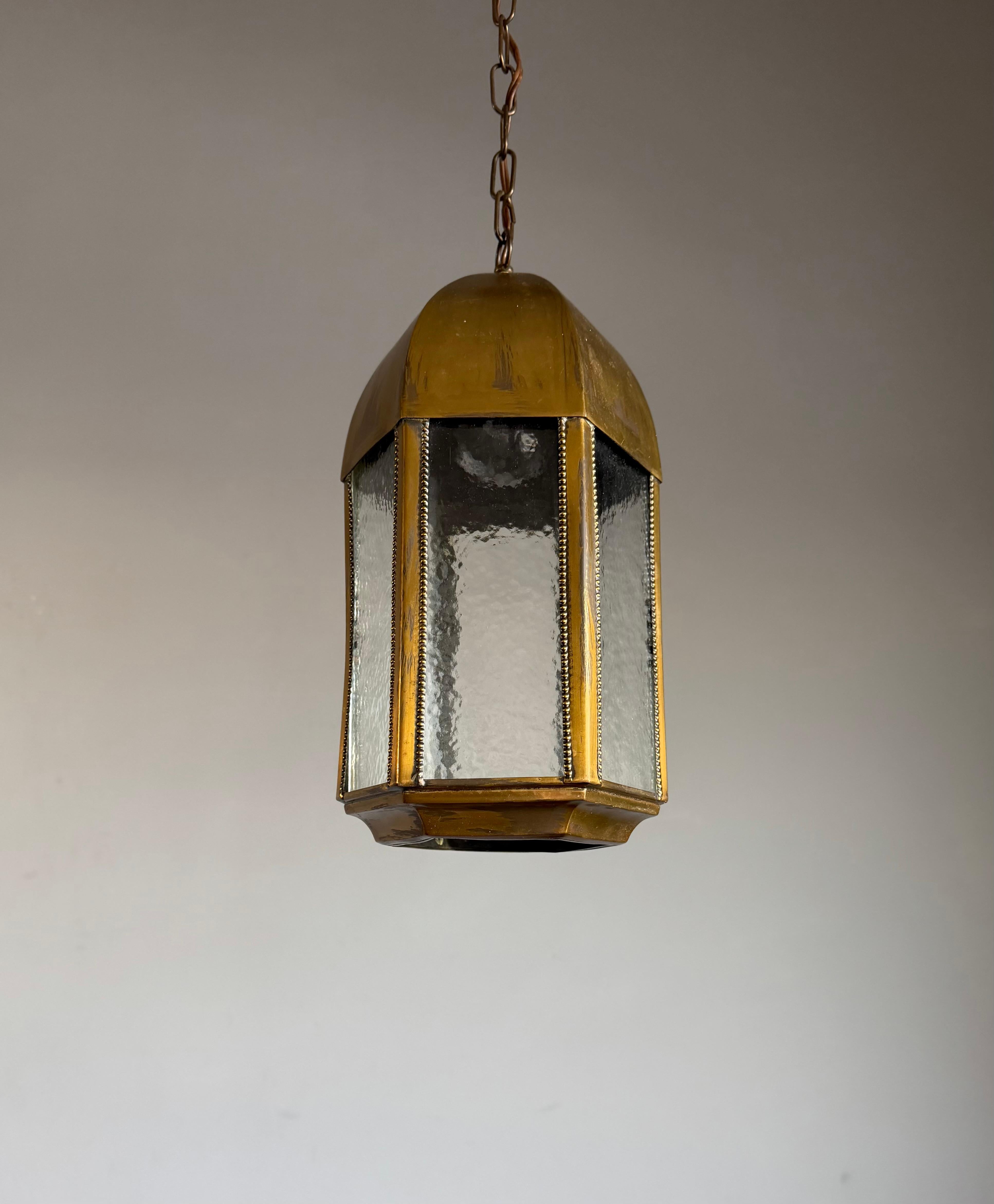 Lámpara colgante de estilo gótico con cúpula, hacia 1920.

Esta preciosa lámpara colgante de latón antiguo tiene una presencia tan tranquila y atemporal. La combinación de su cálido latón envejecido y el cristal catedral de suave textura ámbar crea