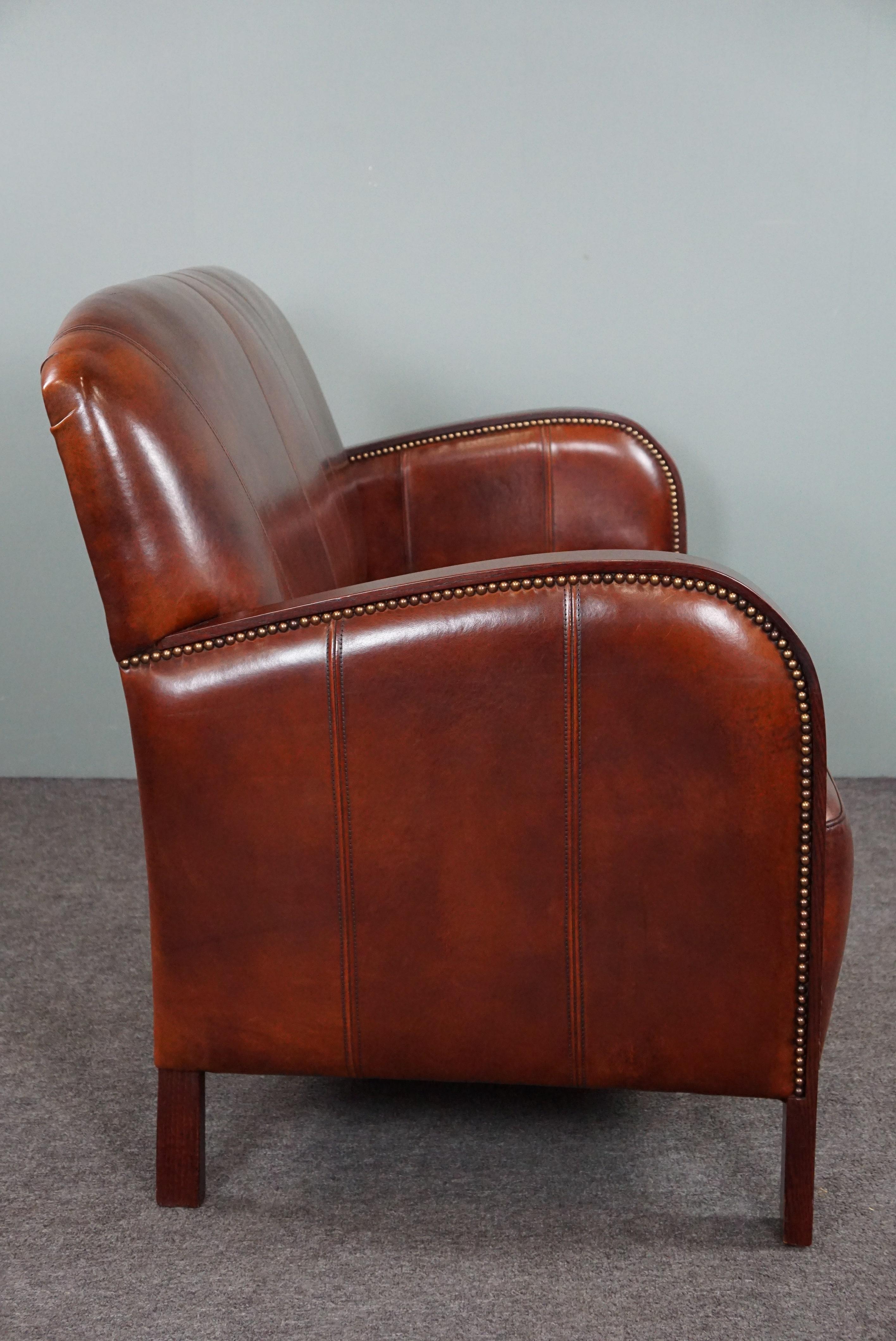 Dieses bequeme Art Deco 2-Sitzer Sofa aus Schafsleder hat eine schöne dunkle Farbe und schöne runde Armlehnen aus Holz. Darüber hinaus besticht dieses Sofa durch sein auffälliges Design und die schön geformte Rückenlehne.

NB:
Die in unserem