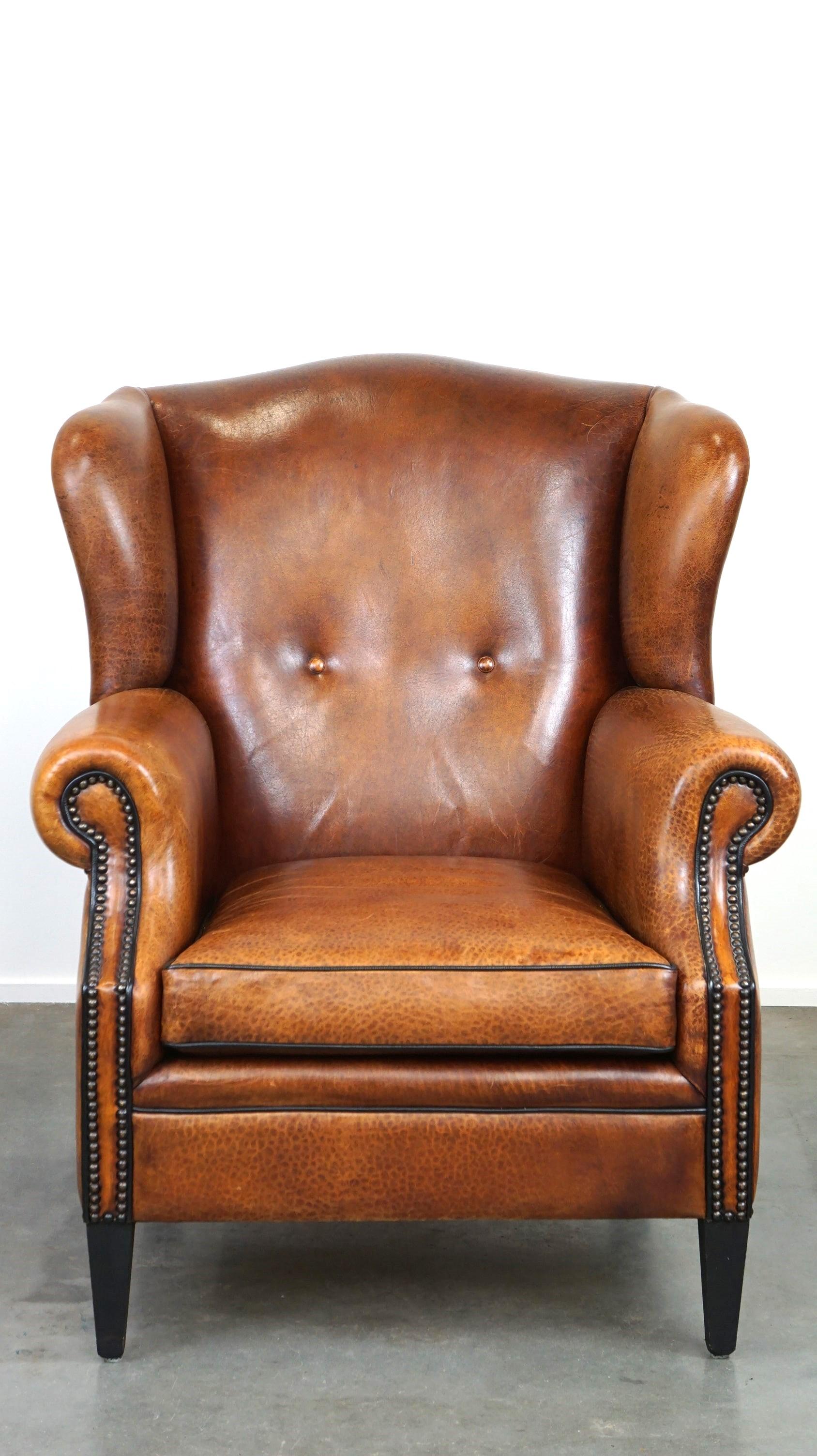 Offered: this beautiful and in good condition wingback armchair made of high-quality sheepskin leather, finished with nails and black piping.

In our opinion, you must have such a wonderful sheepskin leather wingback armchair in your home! It boasts