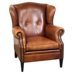 Precioso sillón orejero de piel de oveja, con clavos y ribetes negros