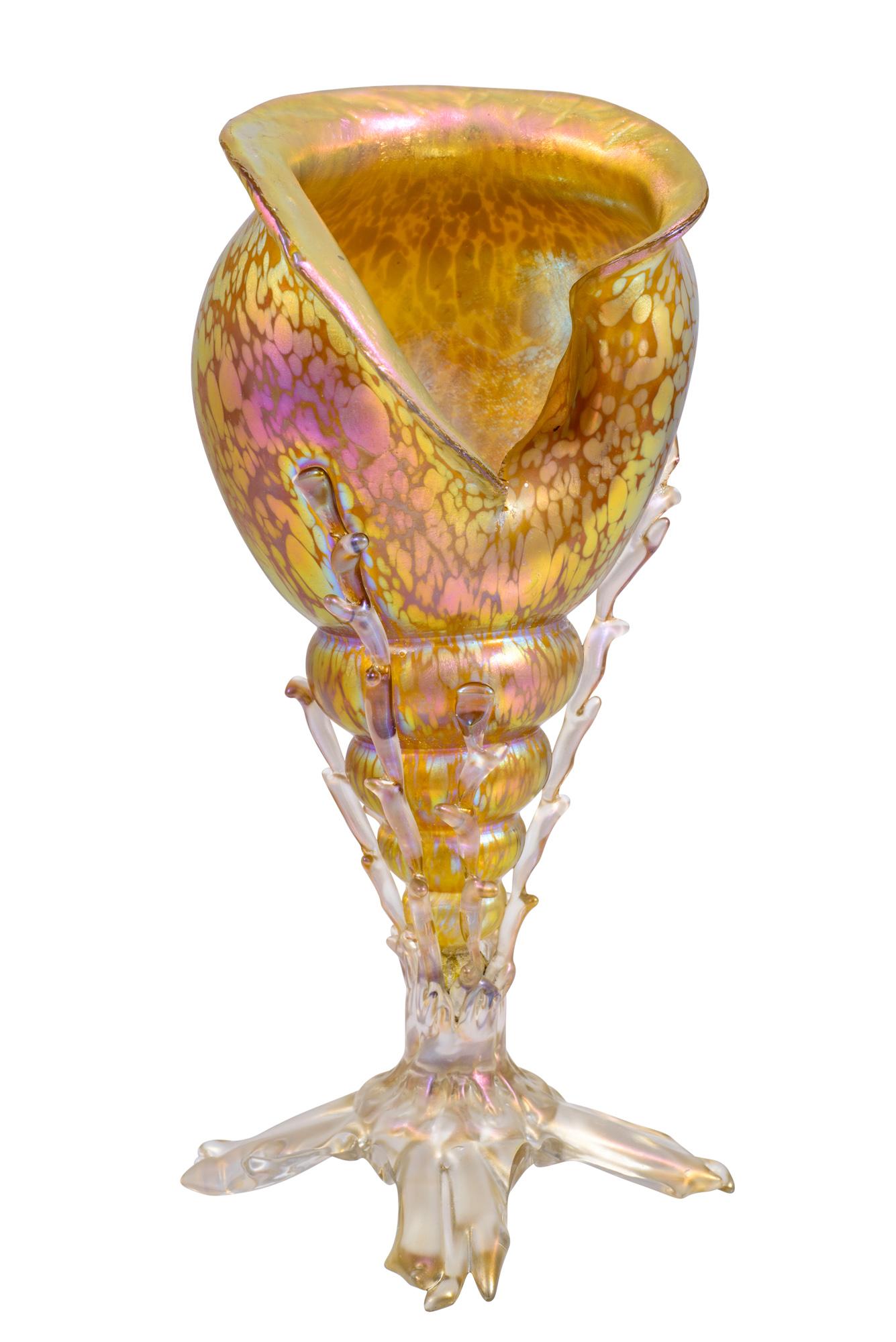 The conch shell shape was one the most popular motifs in the series of naturalistic glasses produced by the glass manufacture Johann Loetz Witwe. Seashells show very different decorations, among them the types Neptun, Diaspora, Astra, several