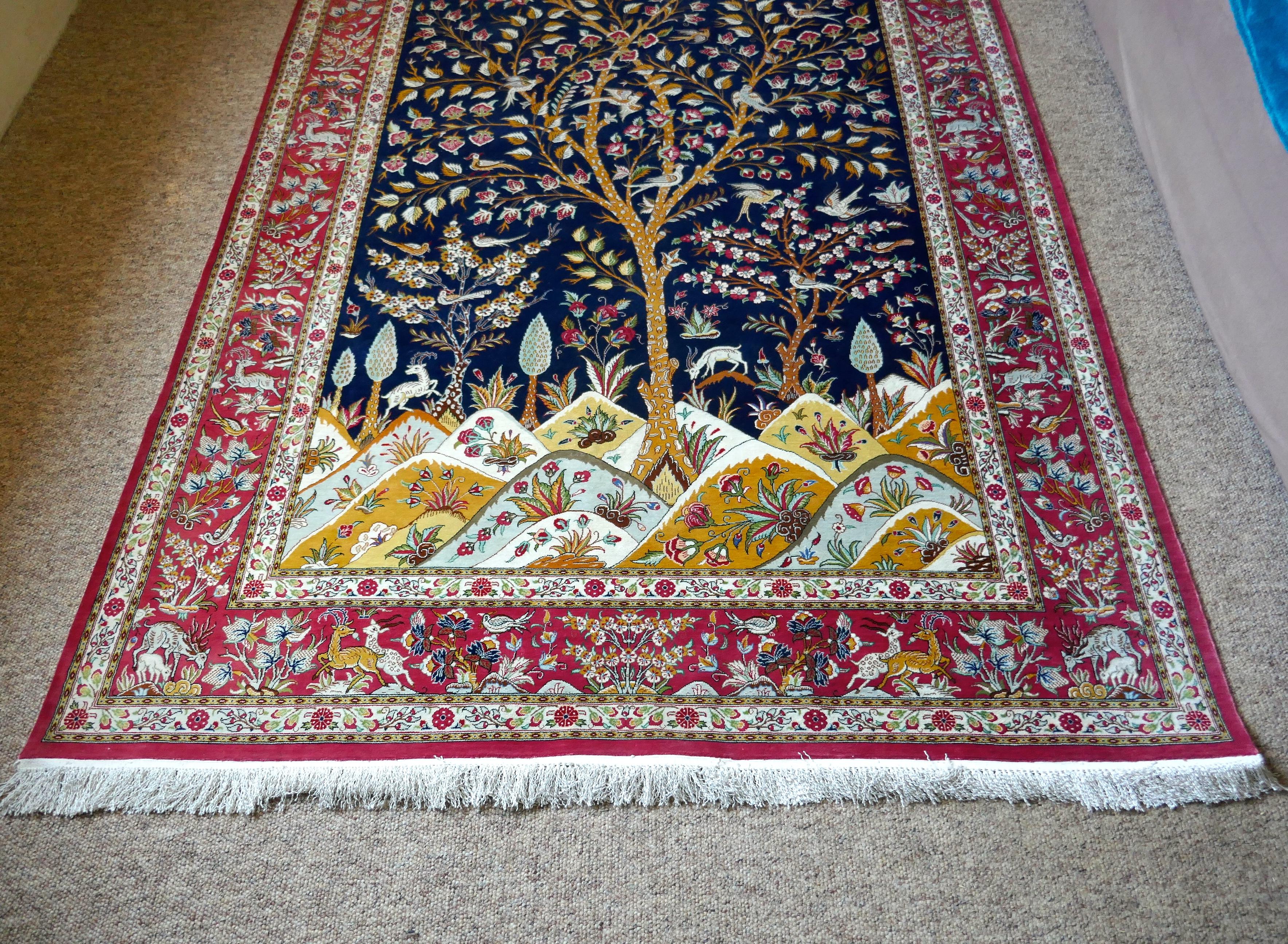 A beautiful signed hand-knotted tree of life pattern Qom Persian silk rug.

The asymmetrical centre panel of this intricate and luscious rug focuses on the iconic tree of life which is surrounded by the birds of paradise on a midnight blue