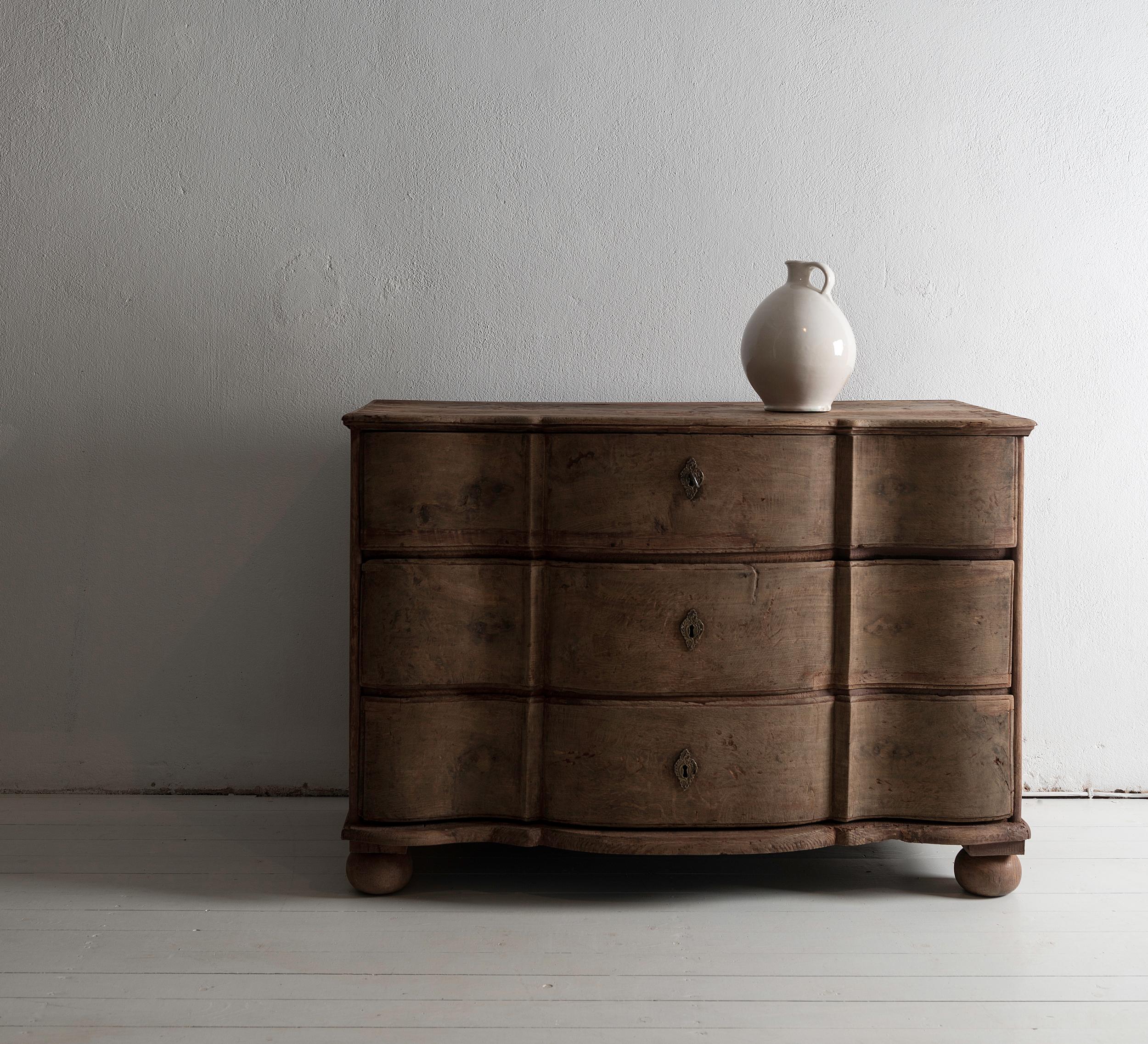 Beautiful simple Swedish 18th century baroque commode Galbée in oak, with remains of original paint. Stunning, authentic piece, proudly showing marks, repairs and alterations. 
A piece of great elegance and purity.