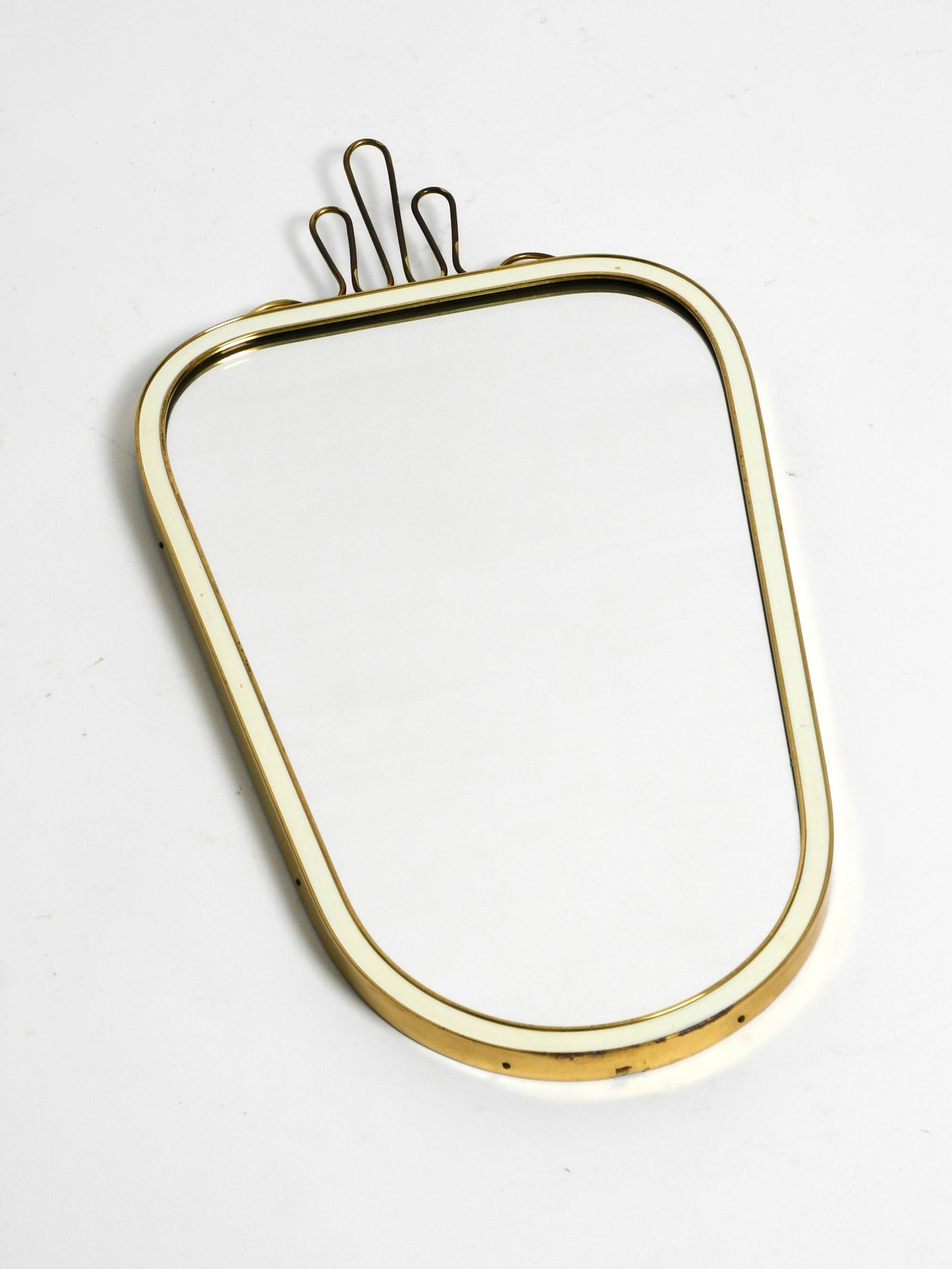 Beautiful heavy small Mid Century brass wall mirror by Münchner Zierspiegel.
Made in Germany. Great 1950s minimalist very elegant design.
Very high quality and elegant workmanship.
A large brass crown is screwed onto the top. The brass frame is