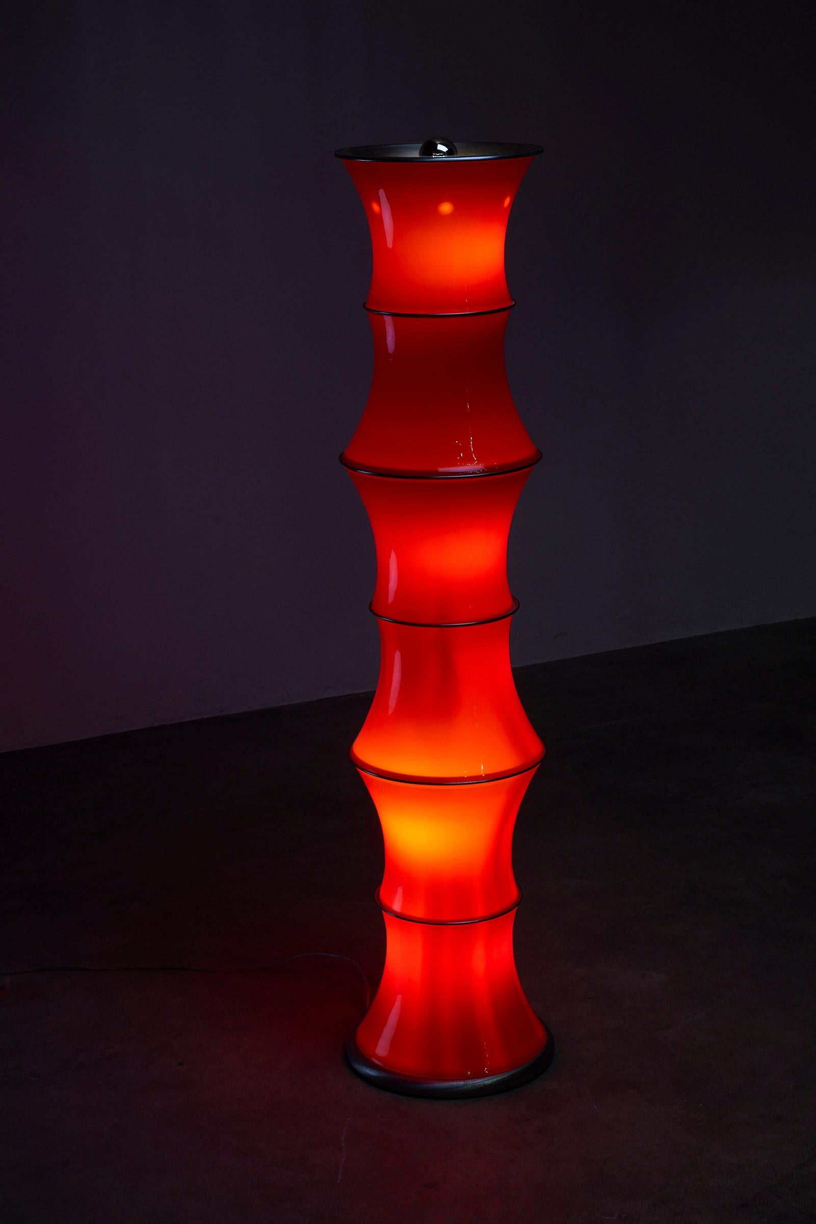 Voici un superbe lampadaire inspiré de l'esthétique du bambou. Fabriquée avec des formes en verre rouge séparées par des éléments métalliques pour le soutien structurel, cette pièce émane de l'élégance et de la sophistication. Le variateur incorporé