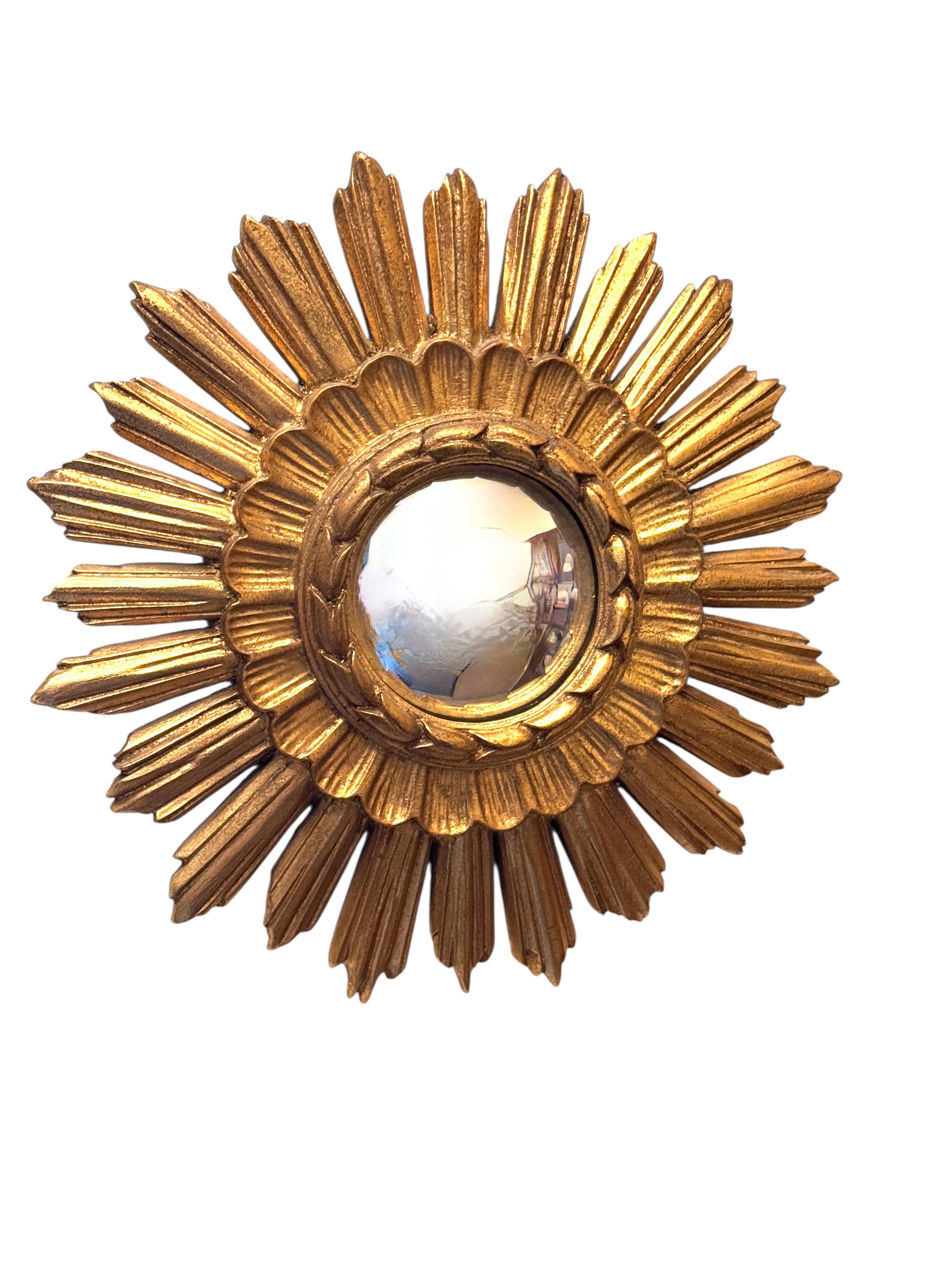 A petite starburst sunburst mirror. Made of gilded resin and wood. It measures approximate 14.5