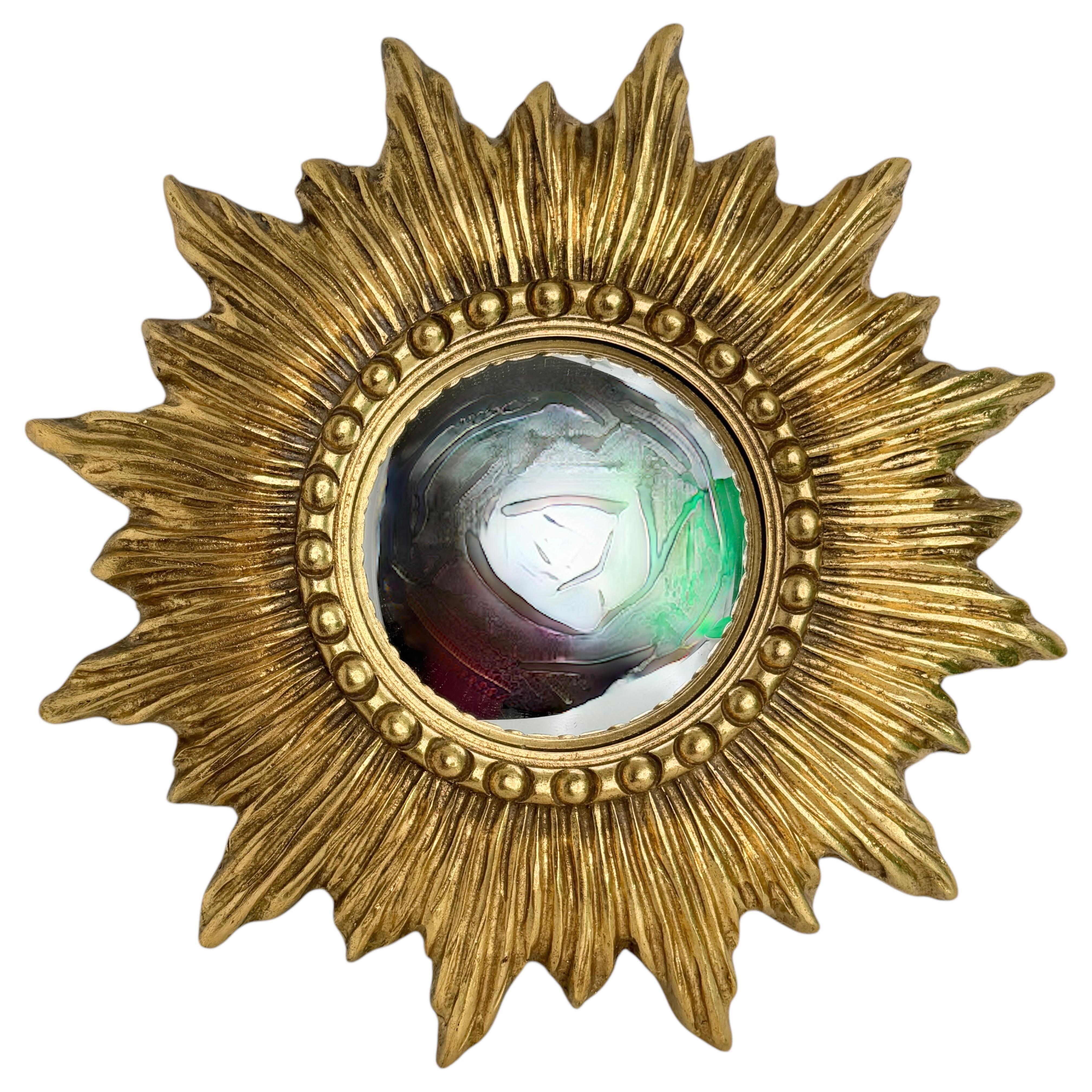 A petite starburst sunburst mirror. Made of gilded resin. It measures approximate 14