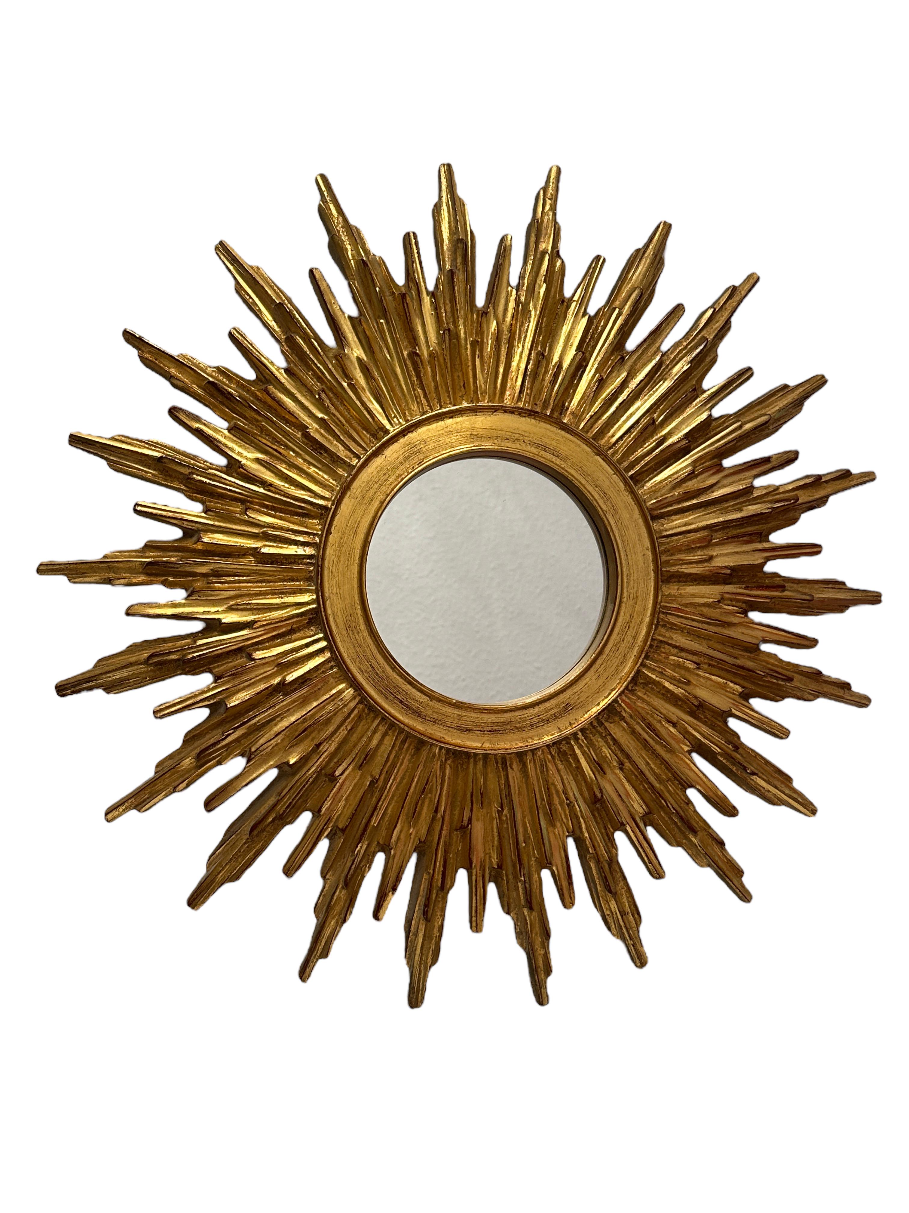 A petite starburst sunburst mirror. Made of gilded resin and wood. It measures approximate 19.38