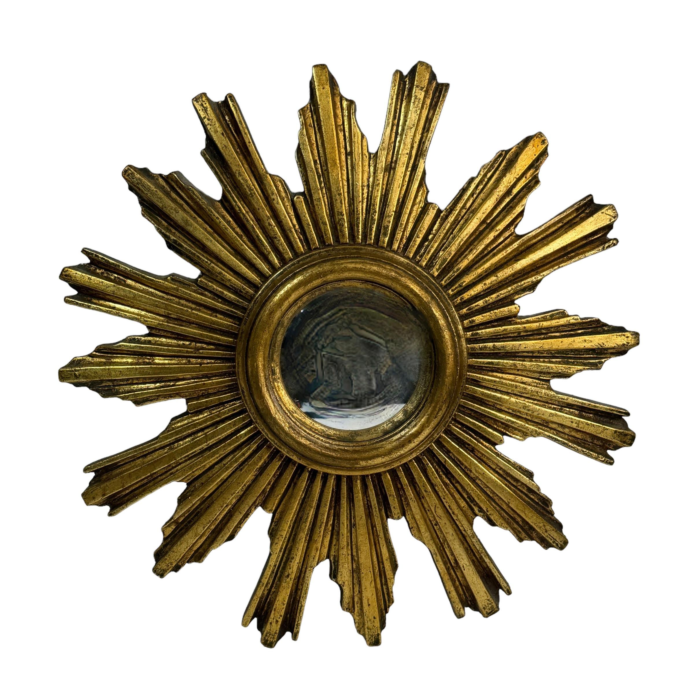 A petite starburst sunburst mirror. Made of gilded resin and wood. It measures approximate 14.5