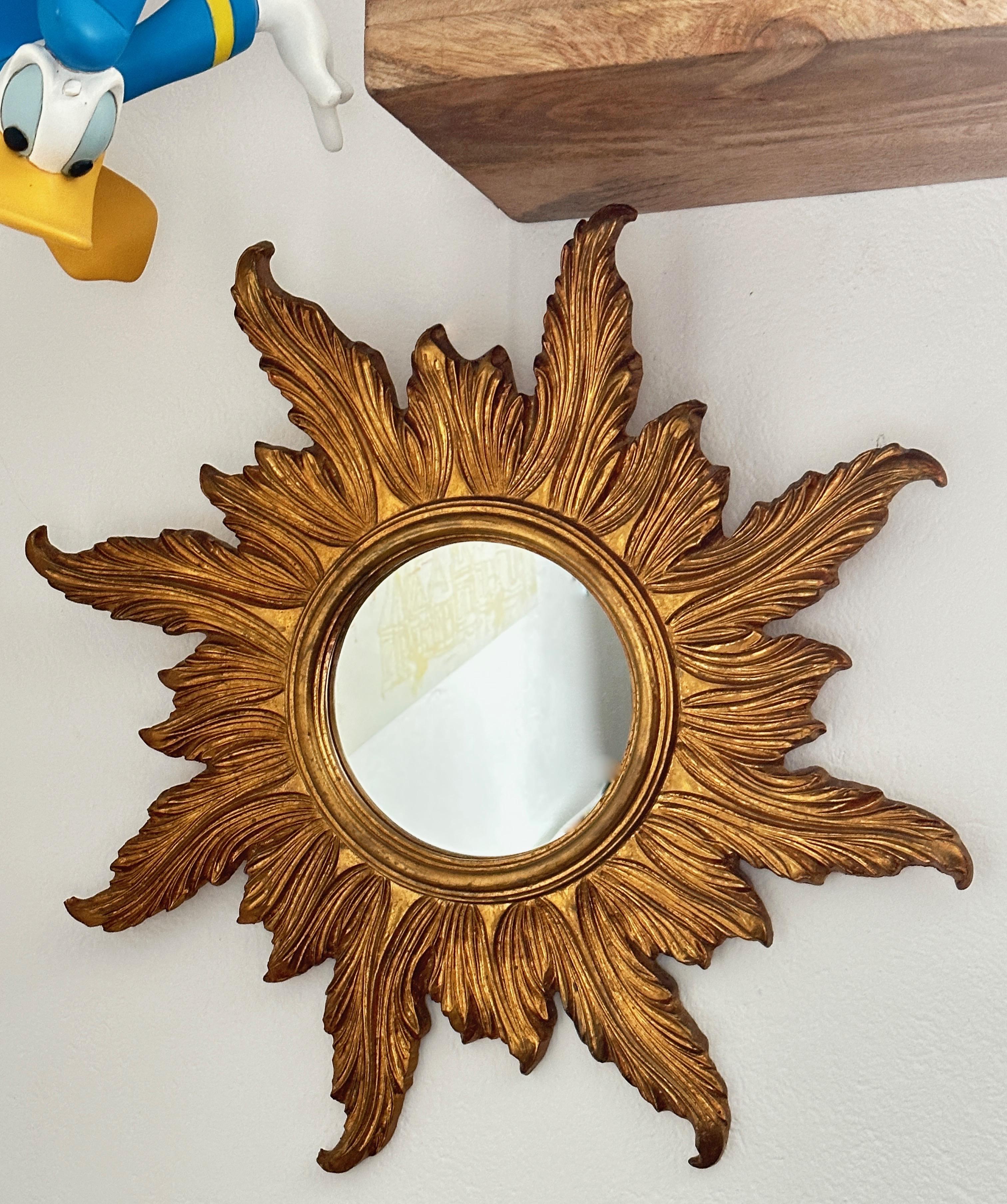 Un beau miroir en forme de starburst. Réalisé en composition dorée et en bois. Il mesure environ 22,63