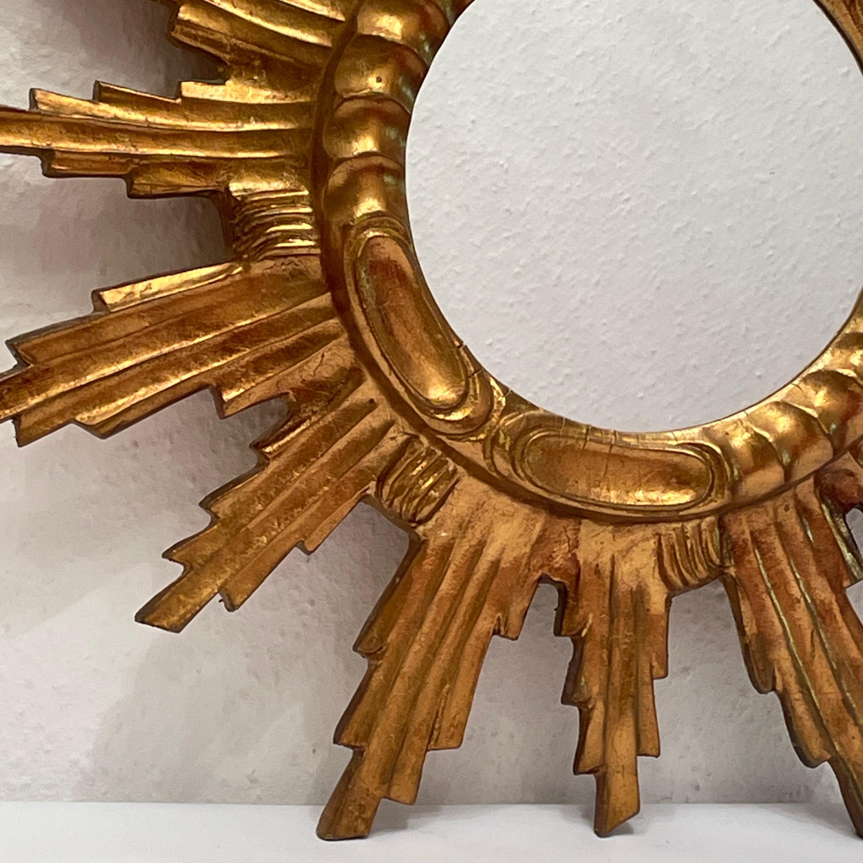 Un beau miroir en forme de starburst. Réalisé en composition dorée et en bois. Il mesure environ 22,13