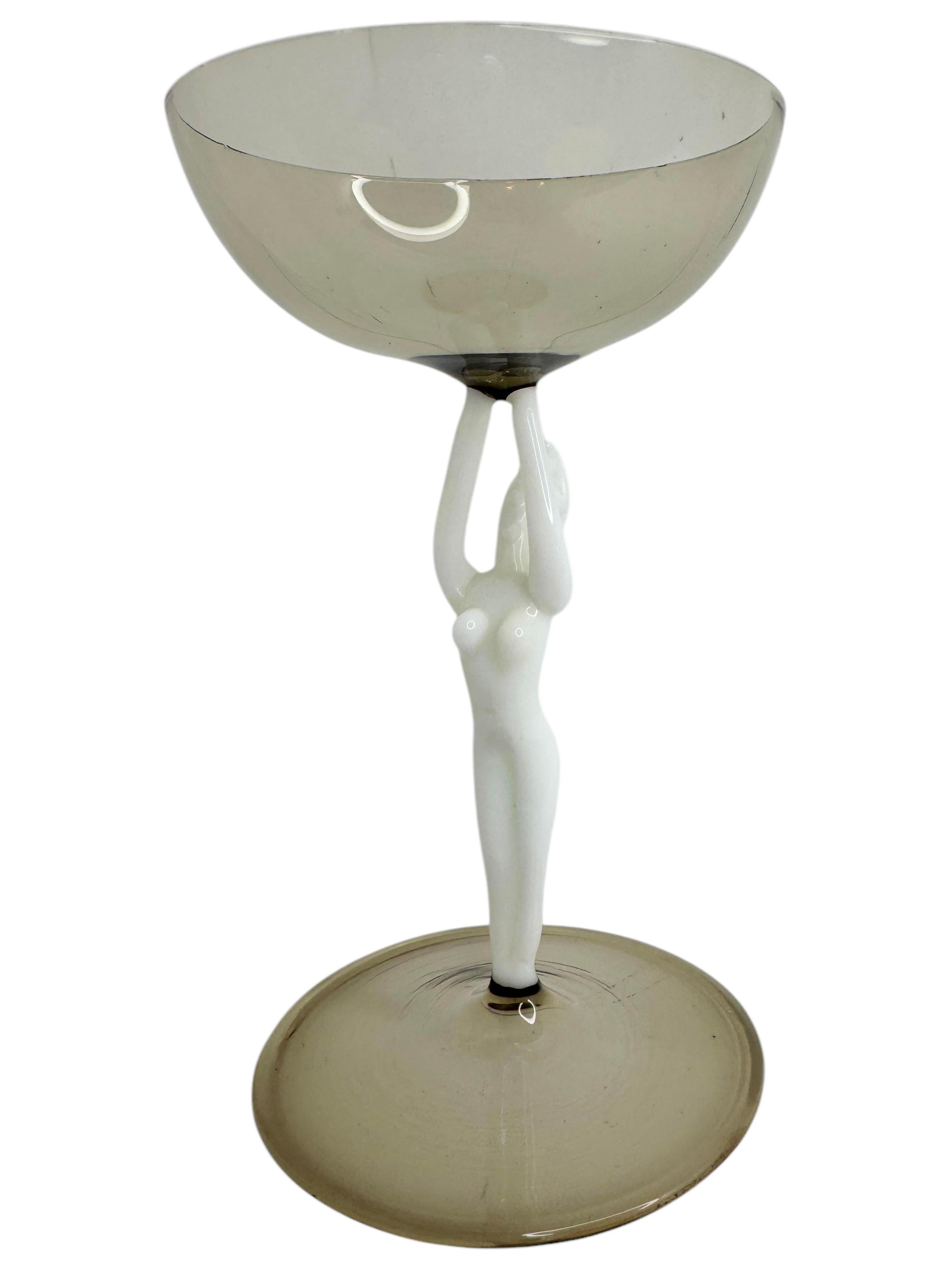 Il s'agit d'un magnifique verre à cocktail à pied d'Autriche. Il présente une tige de femme nue et est dans le style artistique Bimini. Le verre gris a un design en relief, la tige est une femme nue de couleur blanche. La base est un beau verre