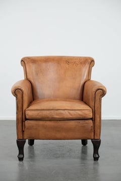Magnifique fauteuil vintage subtil en peau de mouton avec des pieds élégants.