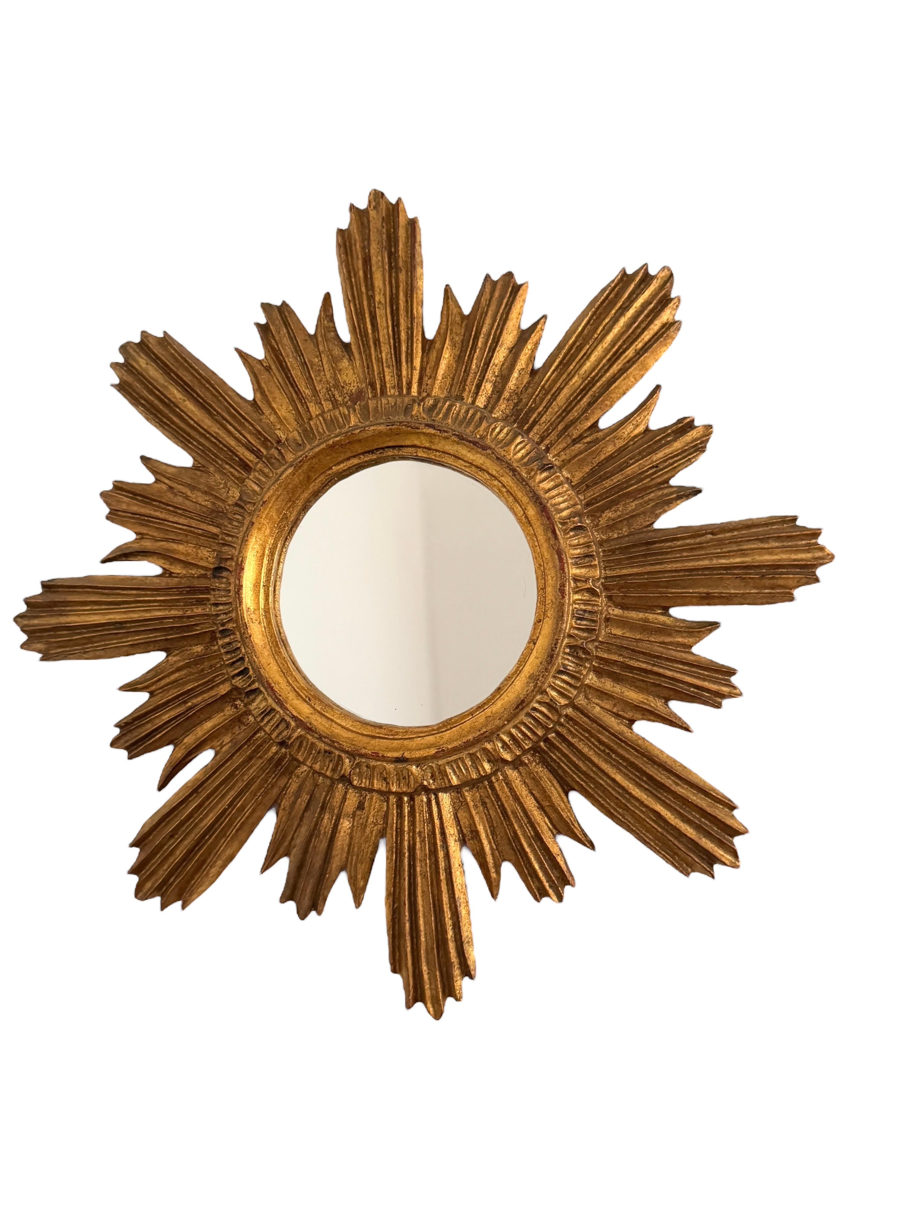 A gorgeous starburst flat mirror. Made of gilded wood and stucco. No chips, no cracks, no repairs. It measures 18 1/3” in diameter, the mirror itself is about 5 5/8