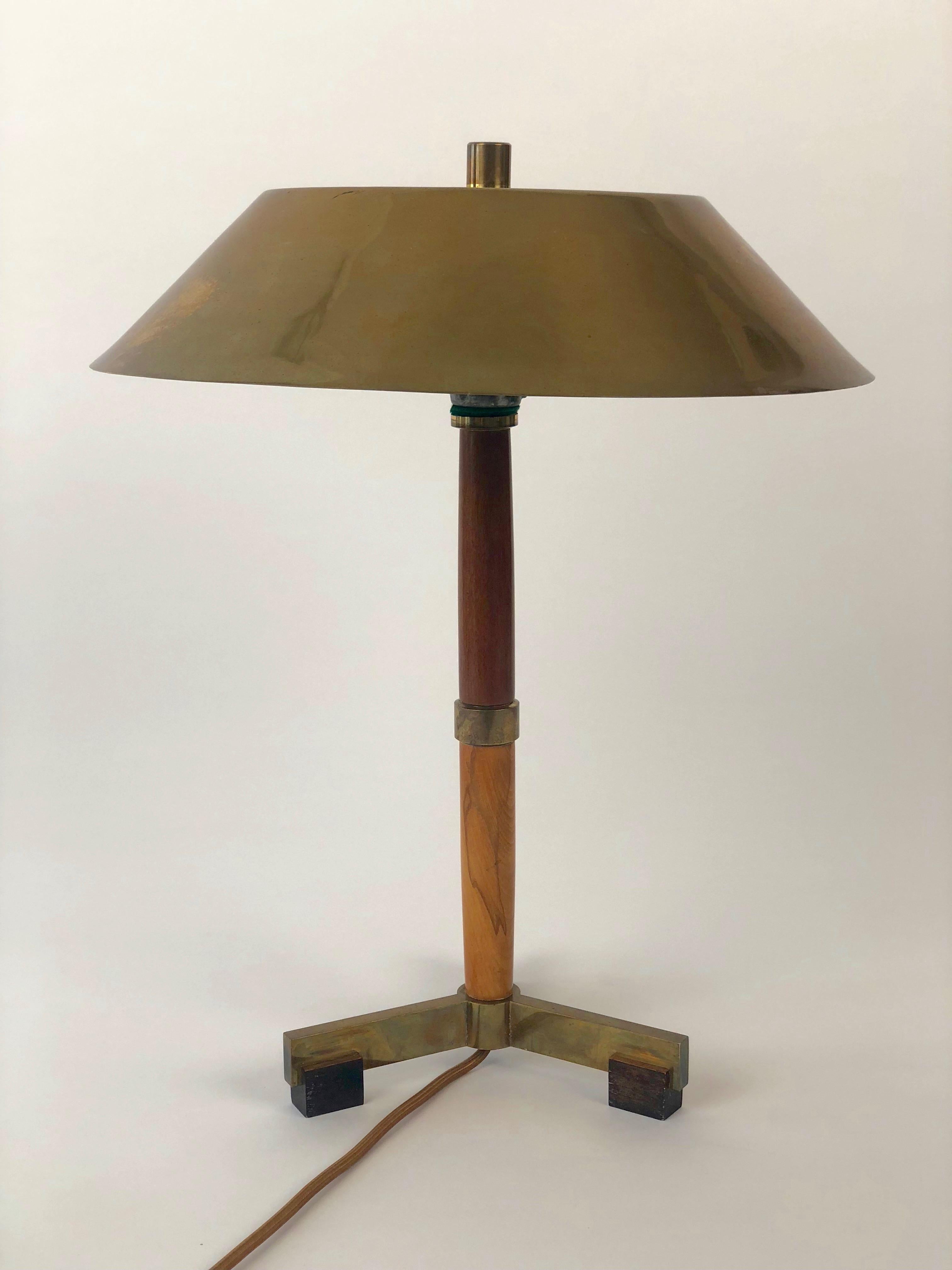 This is a rare table lamp from the 1920's. Based on functional design,it is composed of a massive brass base with mahogany feet. The
column is made up of turned cherry and stained beech wood with a brass spacer separating them . At the top is a