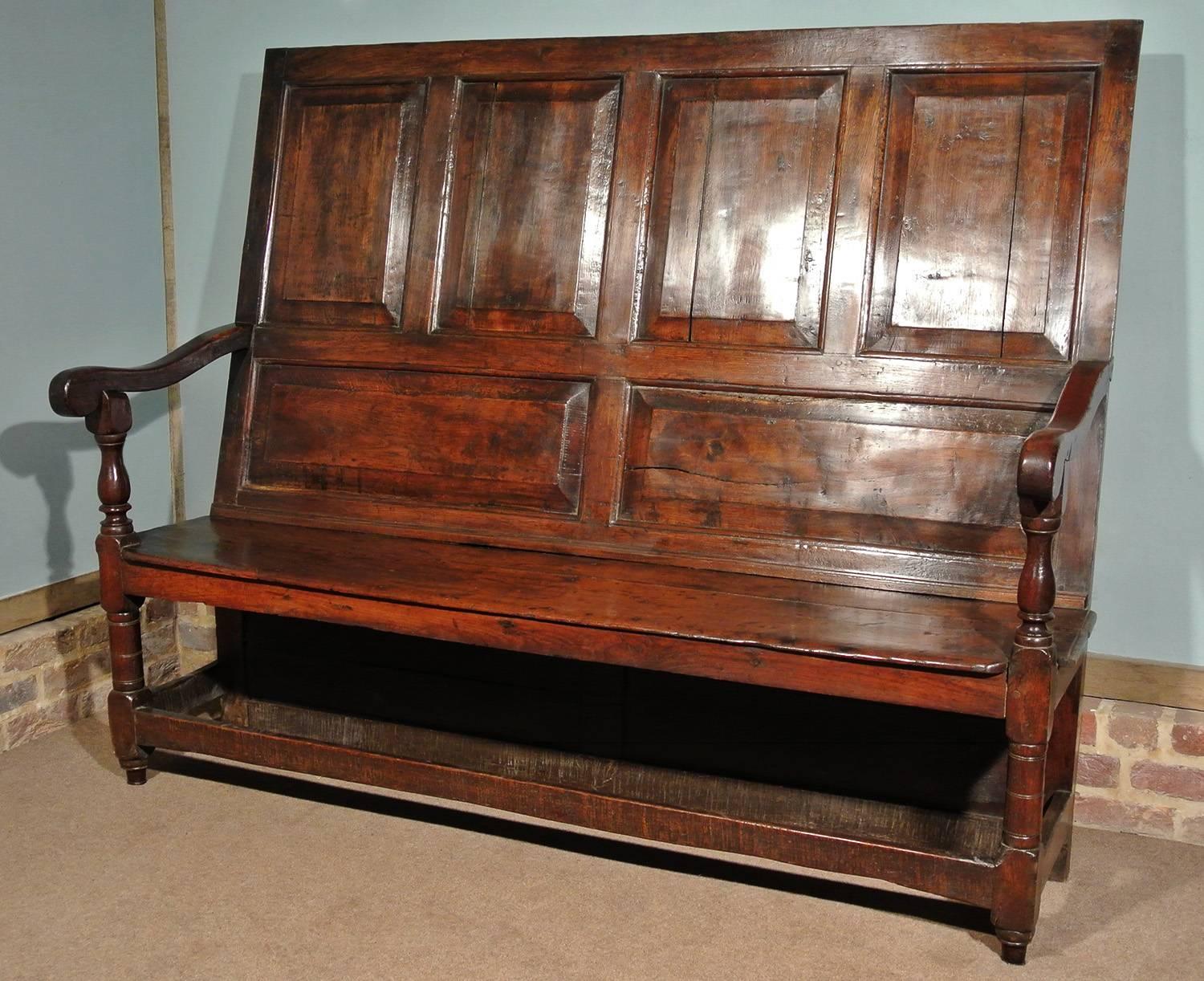 With a fabulous color and natural patina, this early oak and elm settle dates from circa 1680.

The tall back with chamfered and fielded oak panels, the seat with original boards and lovely solid well shaped arms on gunbarrel turned and channel
