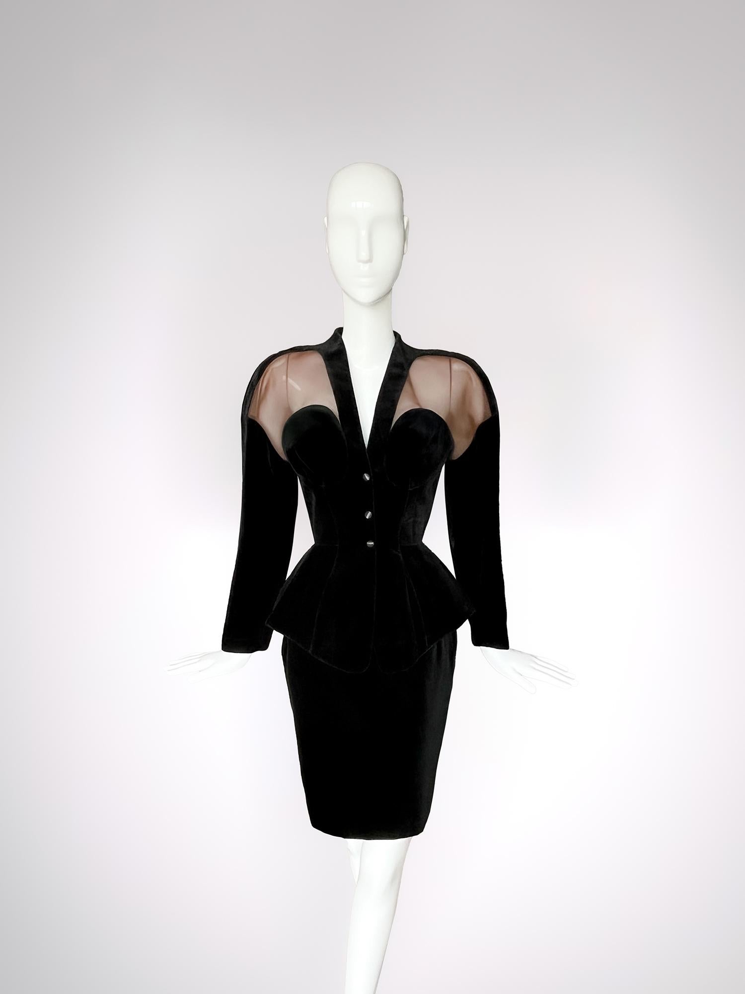 In this stunning Thierry Mugler ensemble, noir becomes a narrative of power, sensuality, and architectural control. Rendered in black velvet with beautiful semi sheer mesh panelling, the look is quintessential Mugler: a hypnotic dialogue between