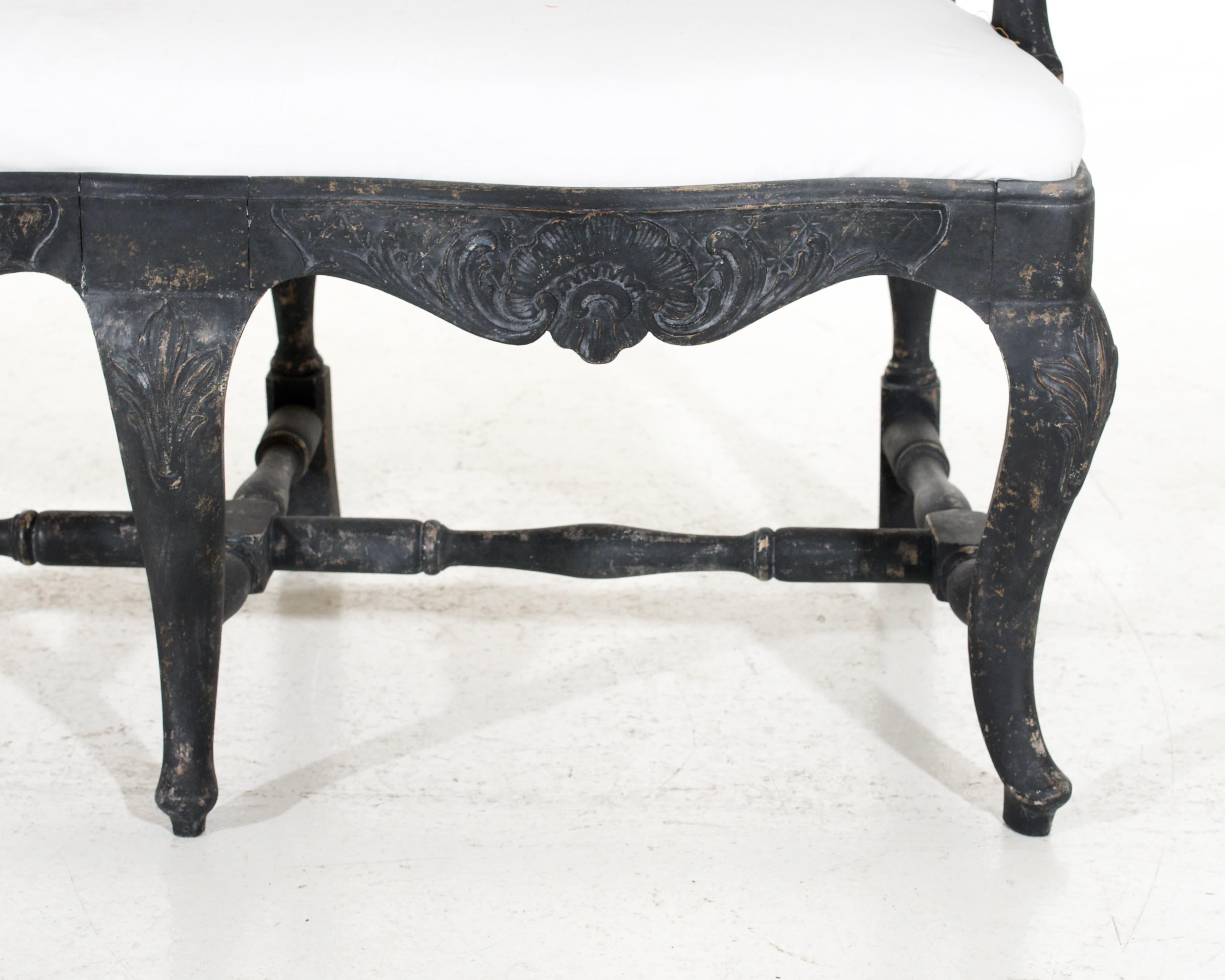 This beautiful three seat sofa-bench was crafted in Sweden over 100 years ago in the classic Rococo style. It features intricate carved detailing, ornate curves and rich upholstery that will bring a touch of elegance to any home.