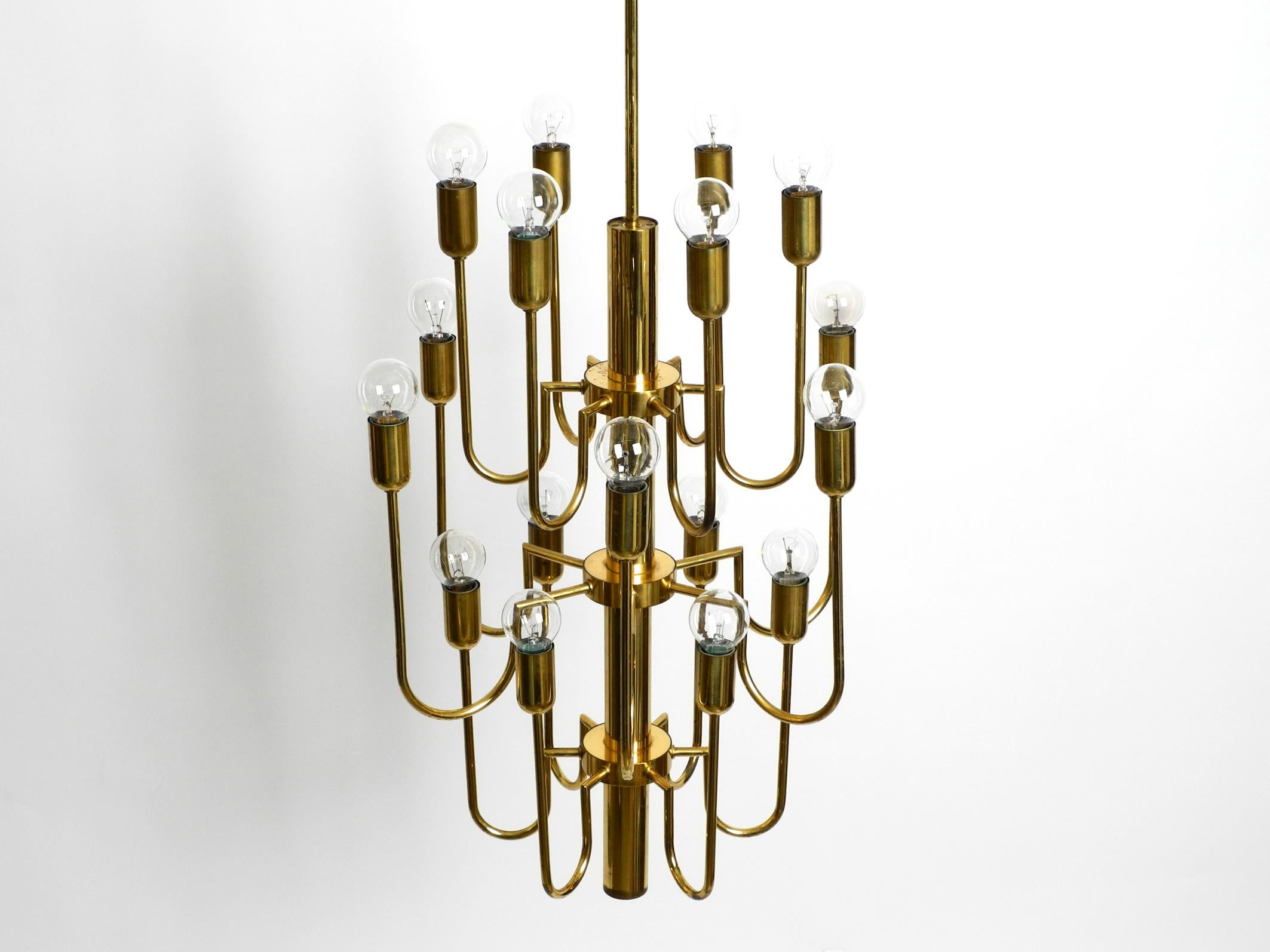 Beautiful Mid Century brass chandelier with a long brass rod. The chandelier has 18 arms, each with one E14 socket up to 40W.
Enough light even for large rooms.
Great extraordinary design from the 1960s.
Frame, rod and canopy are made entirely of